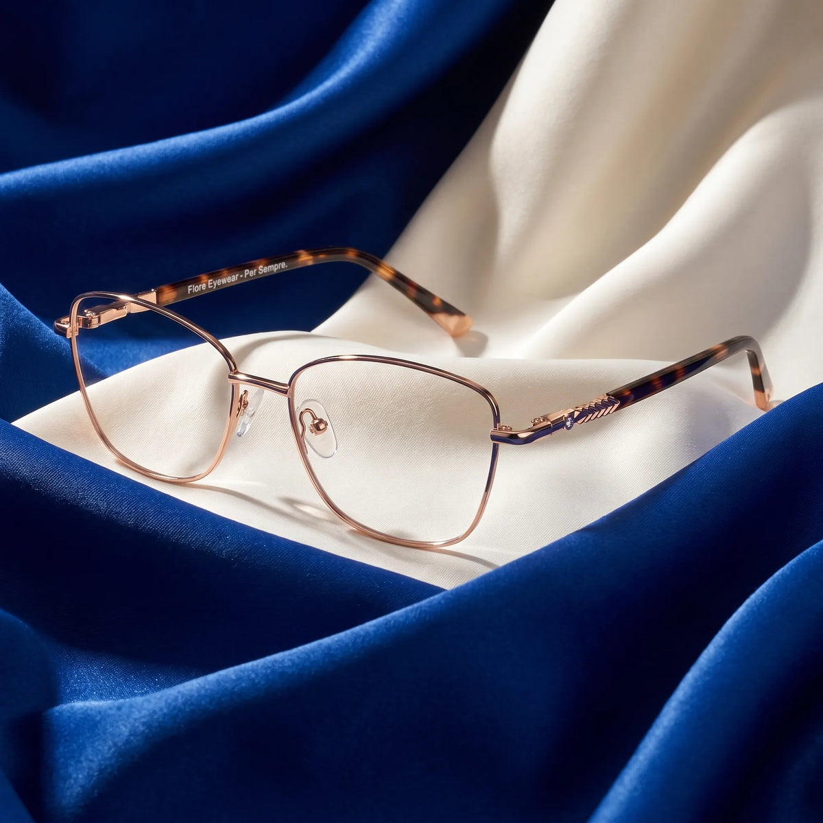 Fiore 2210 eyeglasses in gold pink – resting on draped cobalt and ivory silk