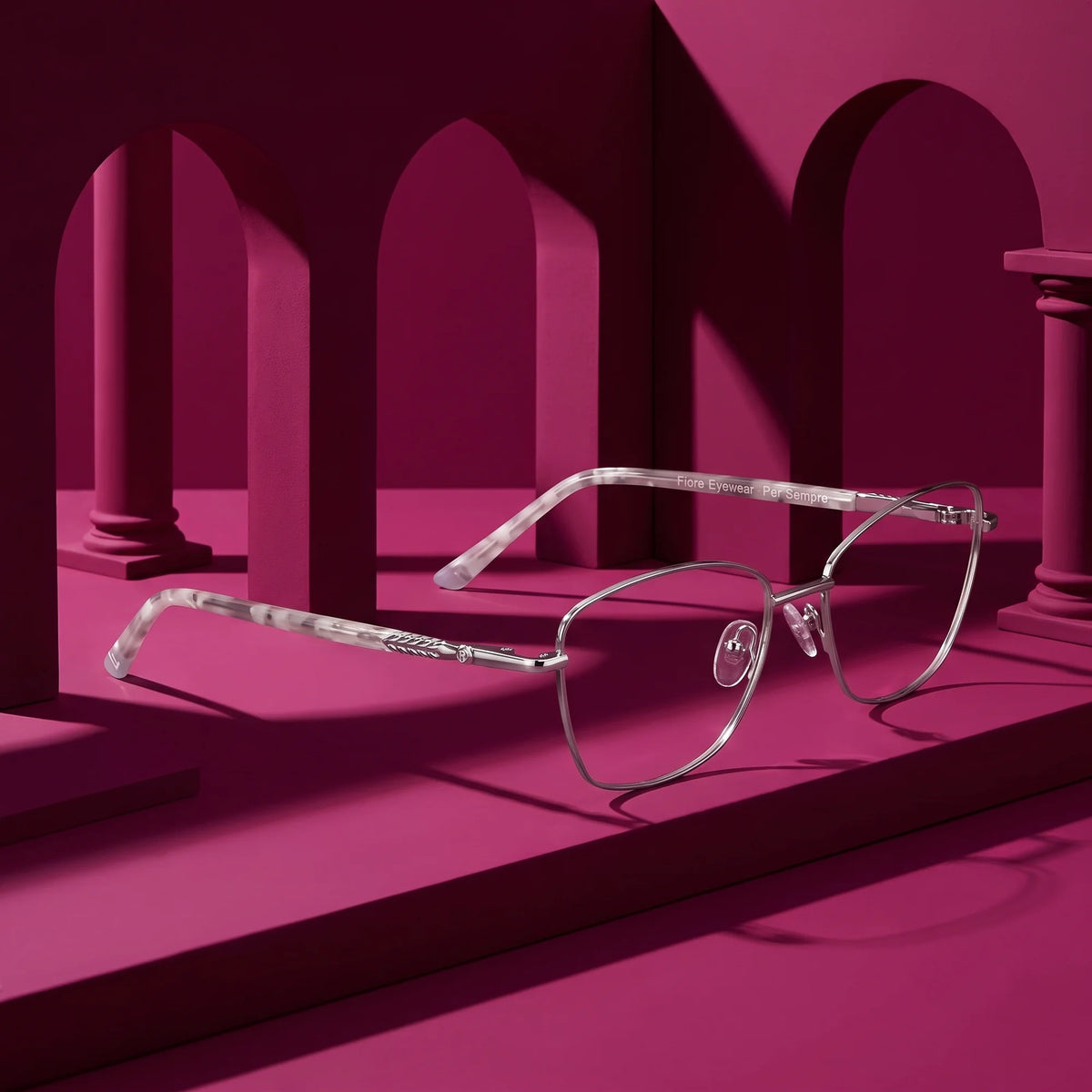 Fiore 2210 eyeglasses in silver black – displayed on a magenta podium among arches