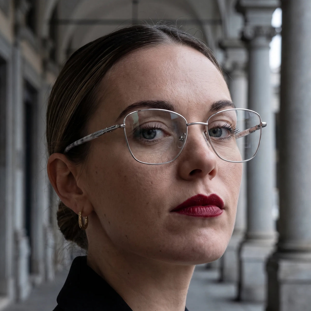 Fiore 2210 eyeglasses in silver black, worn by a model – campaign portrait, moody autumn portrait between stone columns