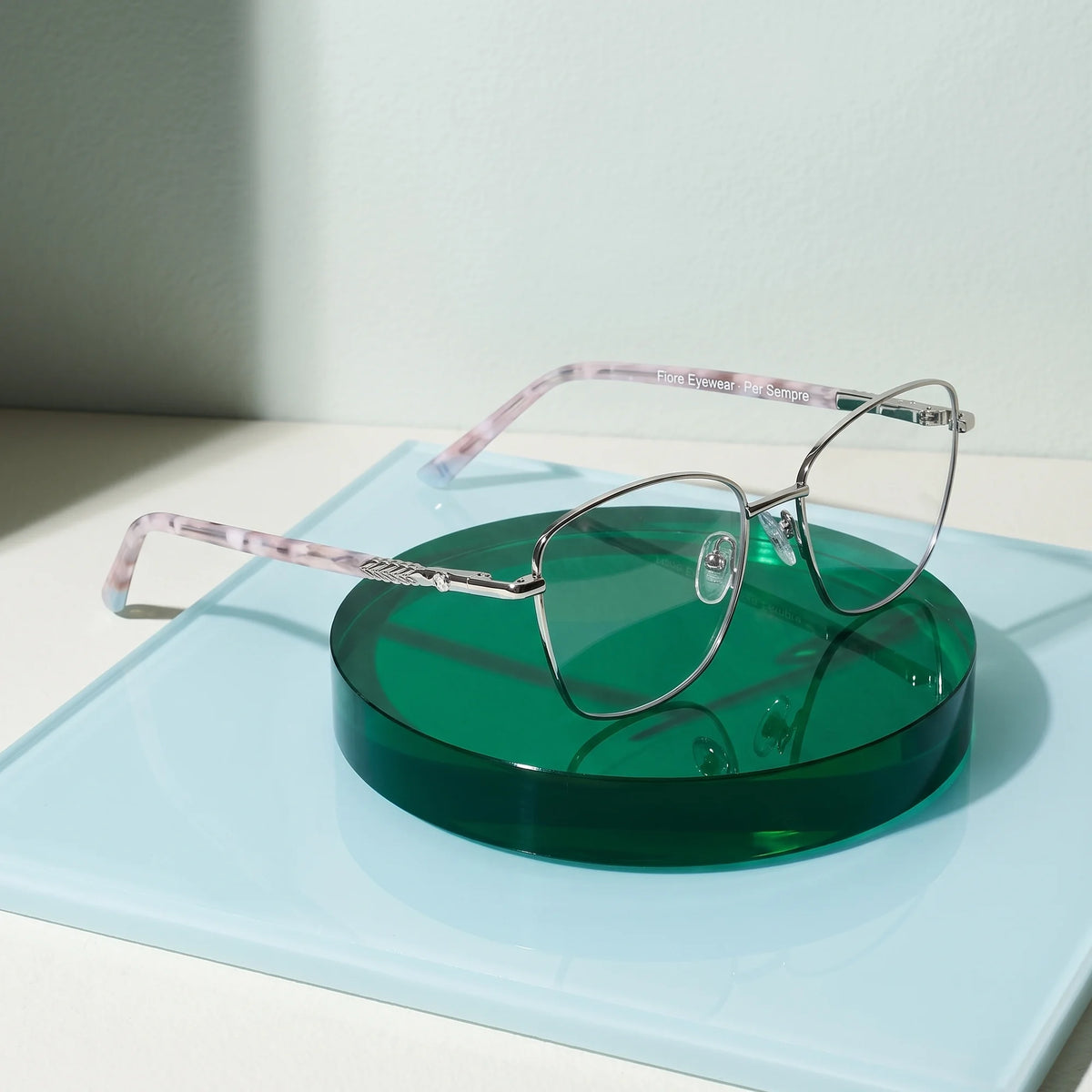Fiore 2210 eyeglasses in silver black – on a cobalt acrylic disc in soft daylight