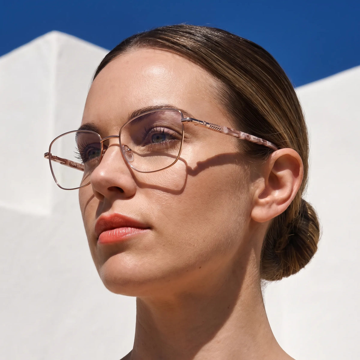 Fiore 2210 eyeglasses in gold brown, worn by a model – campaign portrait, sunlit Balearic whitewash and deep blue sky