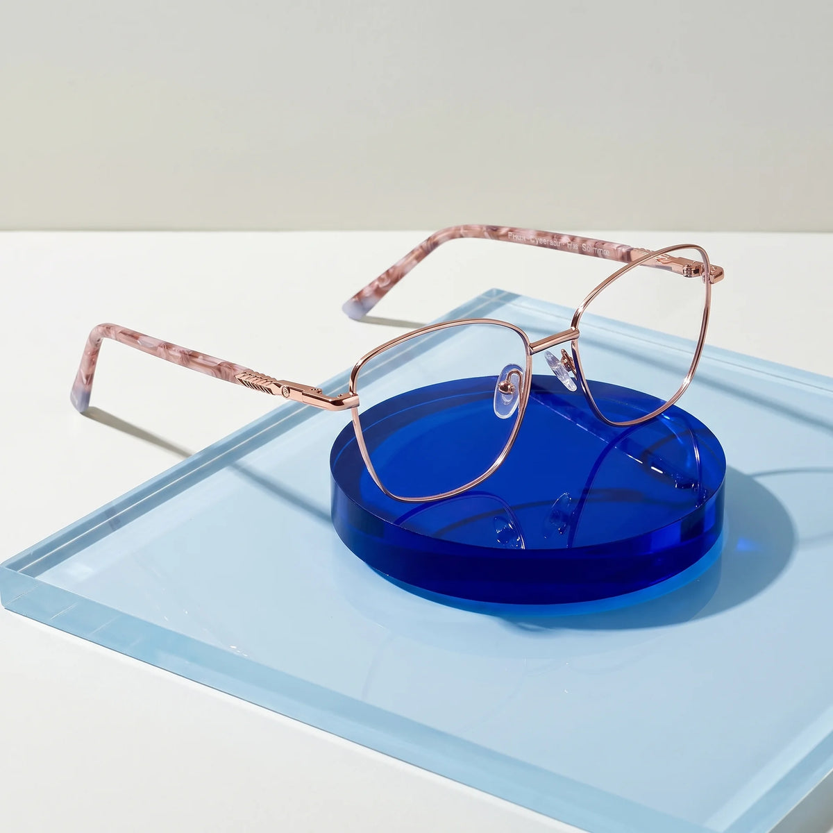 Fiore 2210 eyeglasses in gold brown – on a cobalt acrylic disc in soft daylight