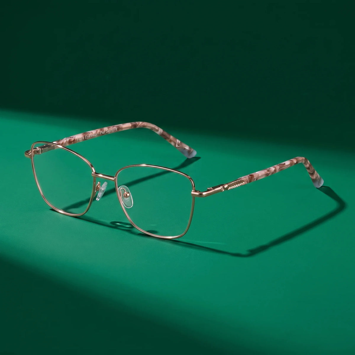 Fiore 2210 eyeglasses in gold brown – editorial still life on a saturated emerald set