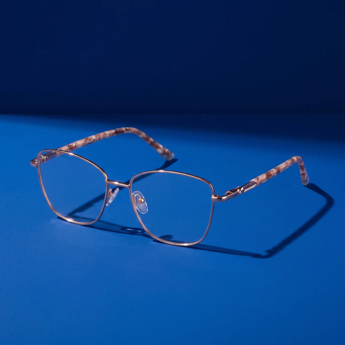 Fiore 2210 eyeglasses in gold brown – still life on a seamless cobalt studio backdrop