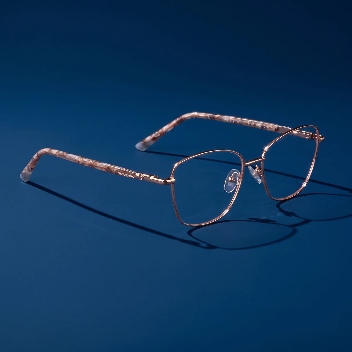 Fiore 2210 eyeglasses in gold brown – hero still life against a deep midnight blue backdrop