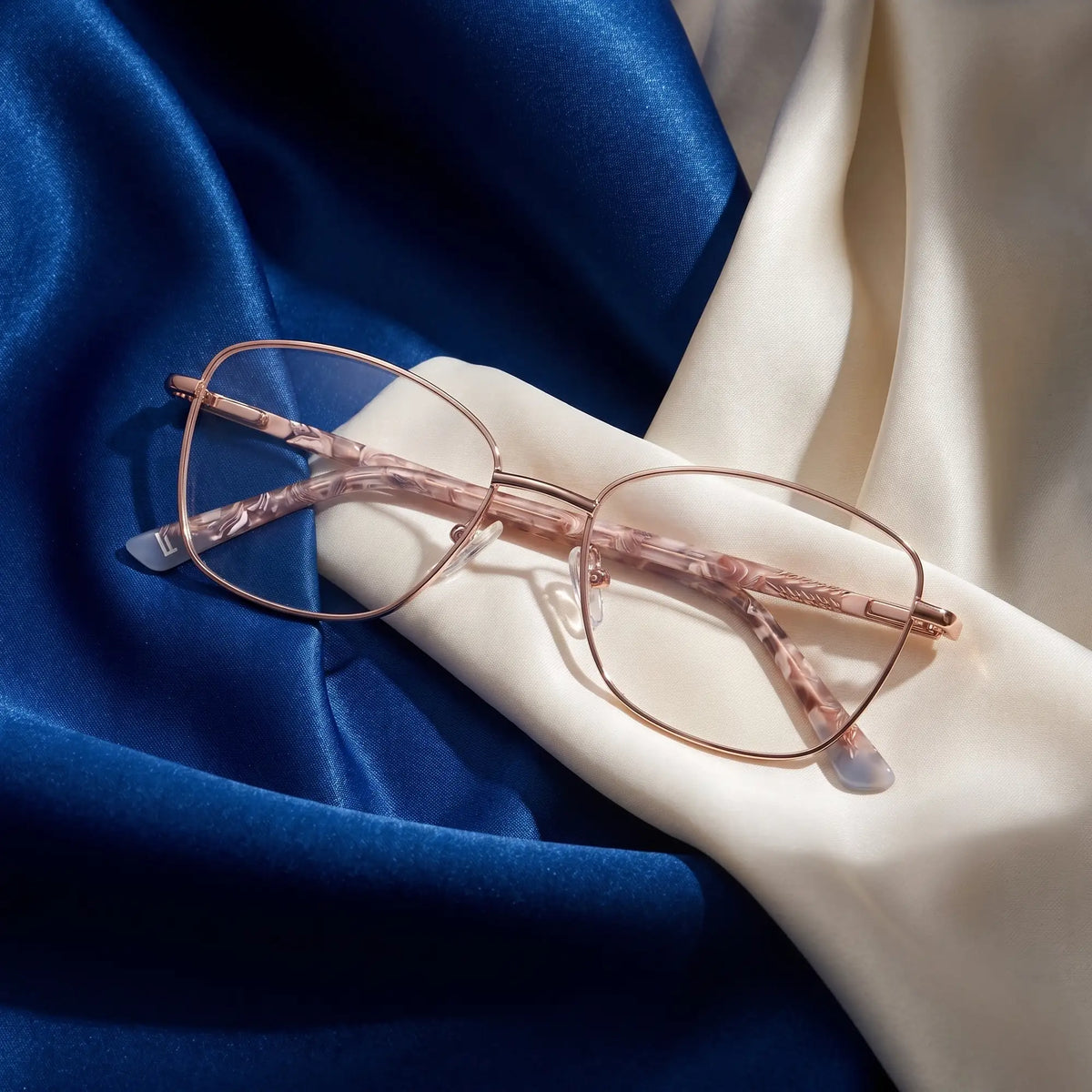 Fiore 2210 eyeglasses in gold brown – resting on draped cobalt and ivory silk