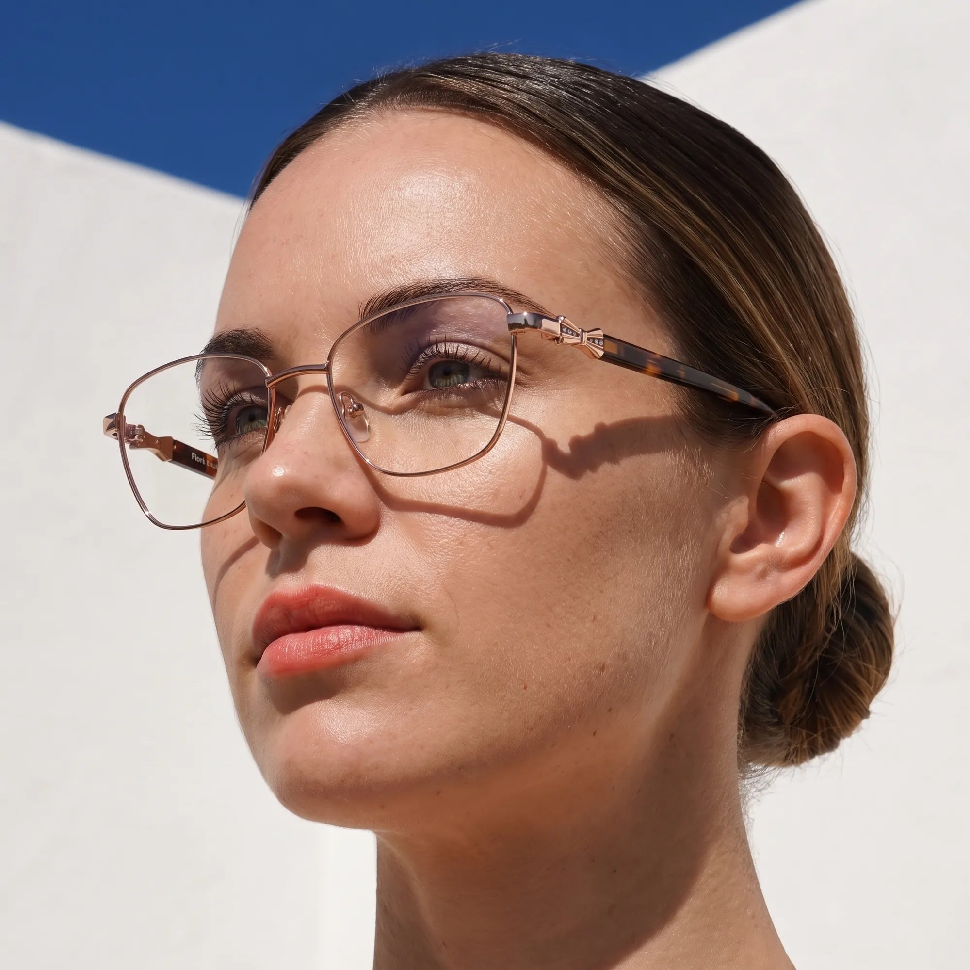 Fiore 22115 eyeglasses in brown, worn by a model – campaign portrait, sunlit Balearic whitewash and deep blue sky