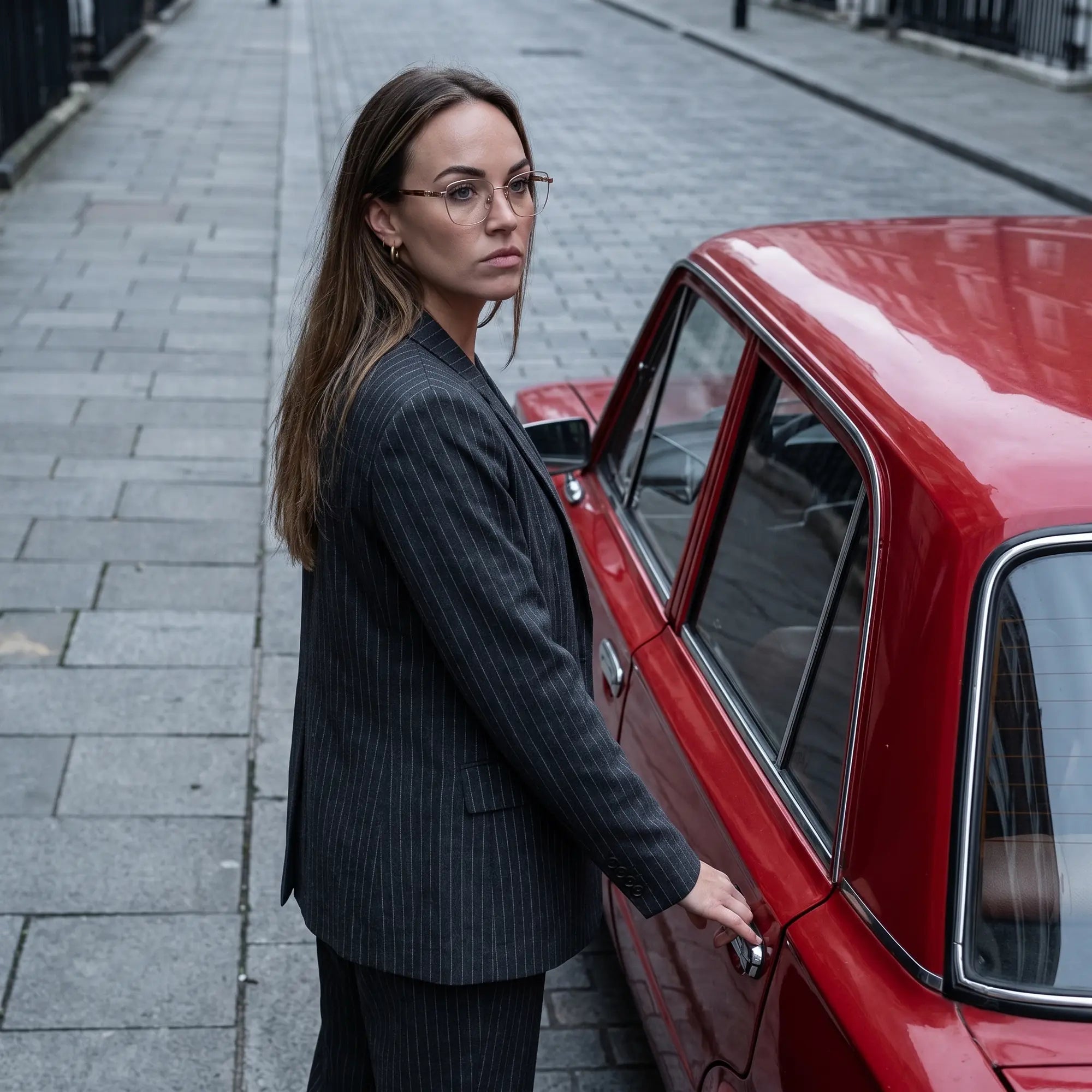 Fiore 22115 eyeglasses in brown, worn by a model – campaign portrait, pinstripe suit beside a classic red car