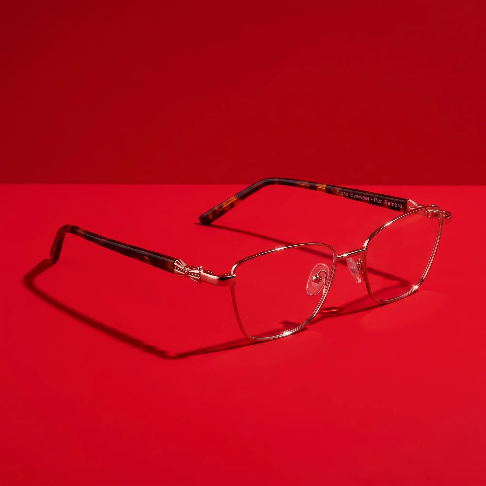 Fiore 22115 eyeglasses in brown – hero still life against a deep vivid red backdrop