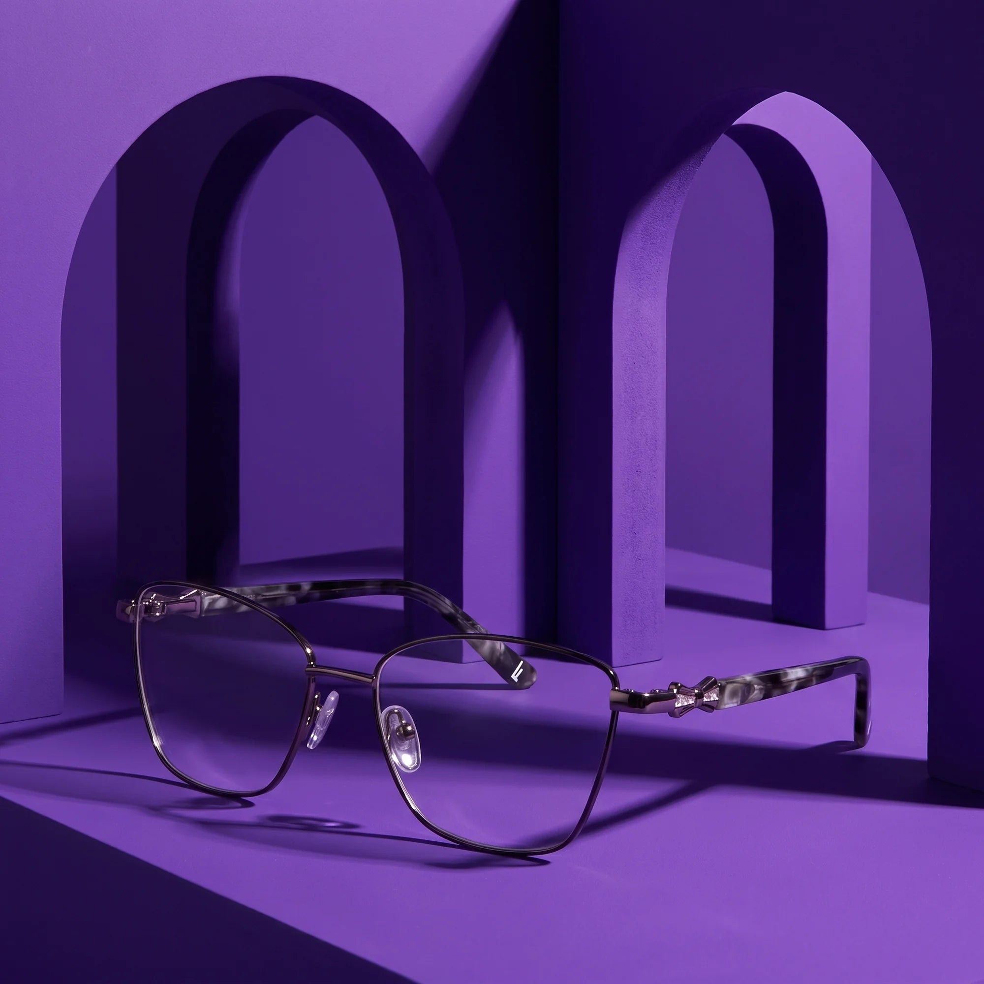 Fiore 22115 eyeglasses in black silver – displayed on a violet podium among arches