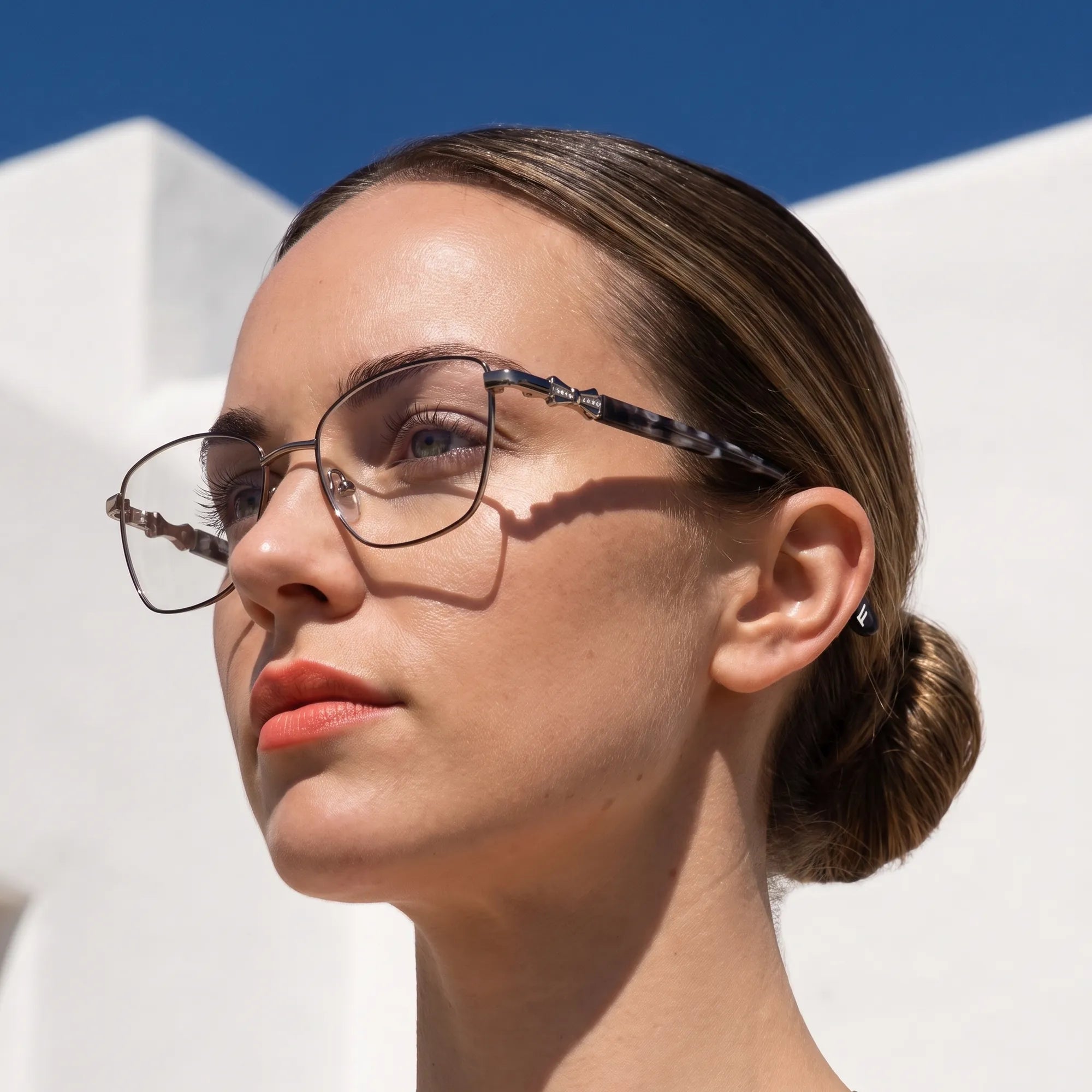 Fiore 22115 eyeglasses in black silver, worn by a model – campaign portrait, sunlit Balearic whitewash and deep blue sky