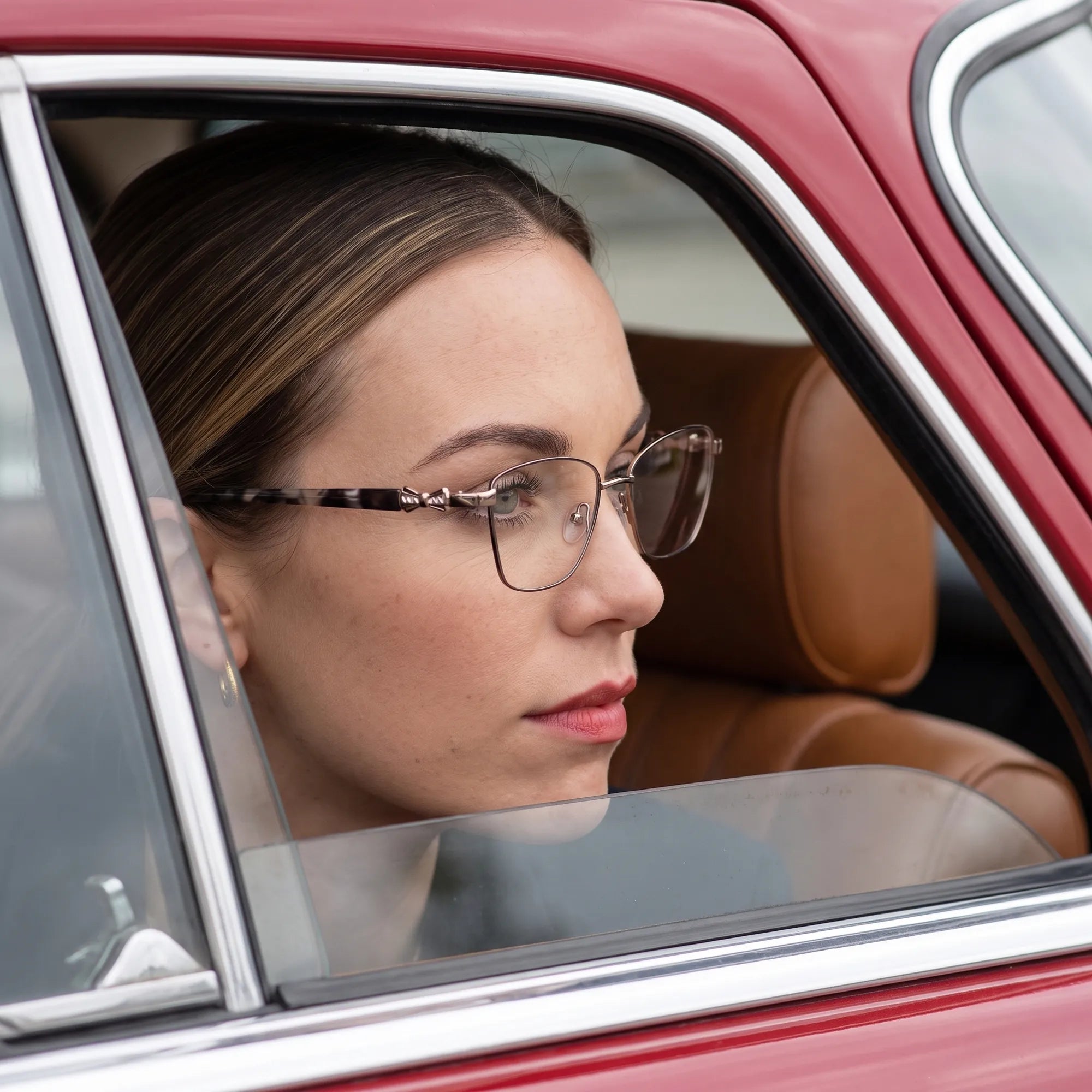 Fiore 22115 eyeglasses in black silver, worn by a model – campaign portrait, gaze through a classic red car window