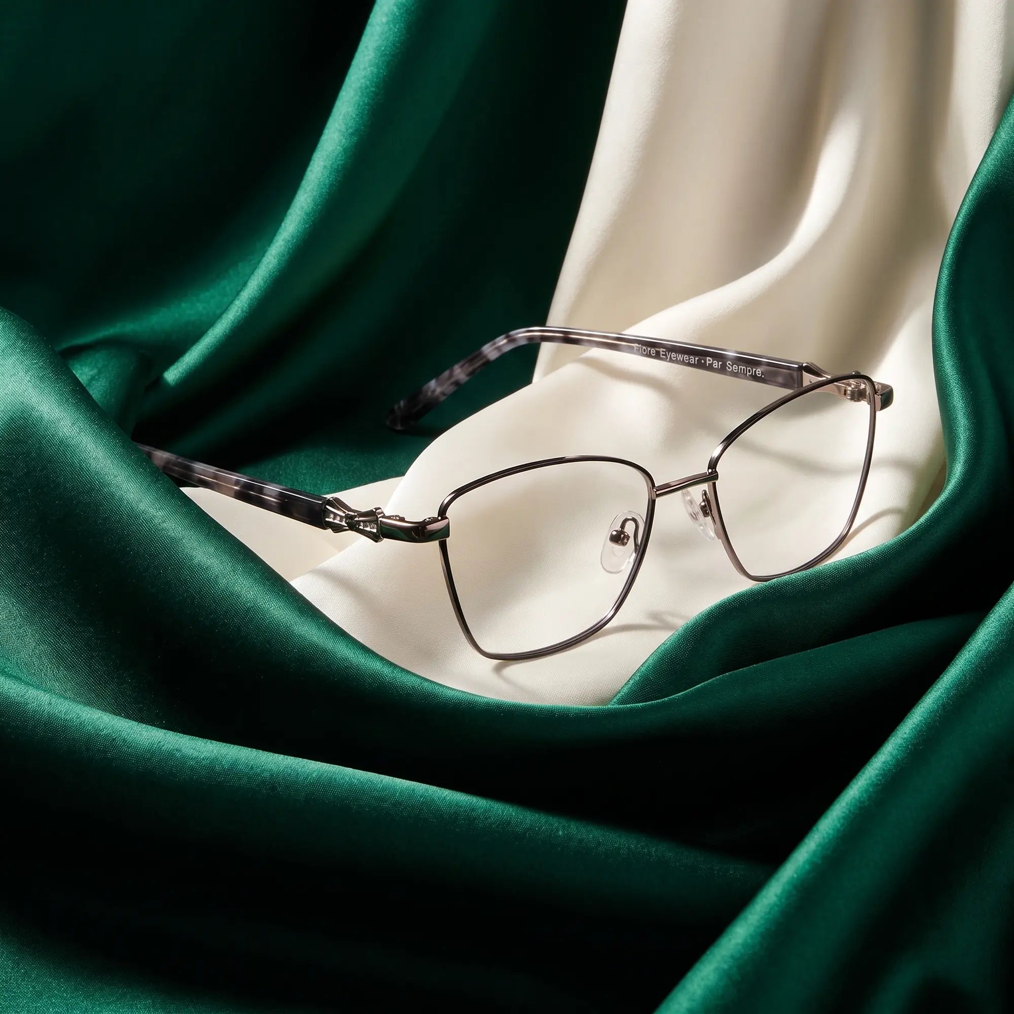 Fiore 22115 eyeglasses in black silver – resting on draped emerald and ivory silk