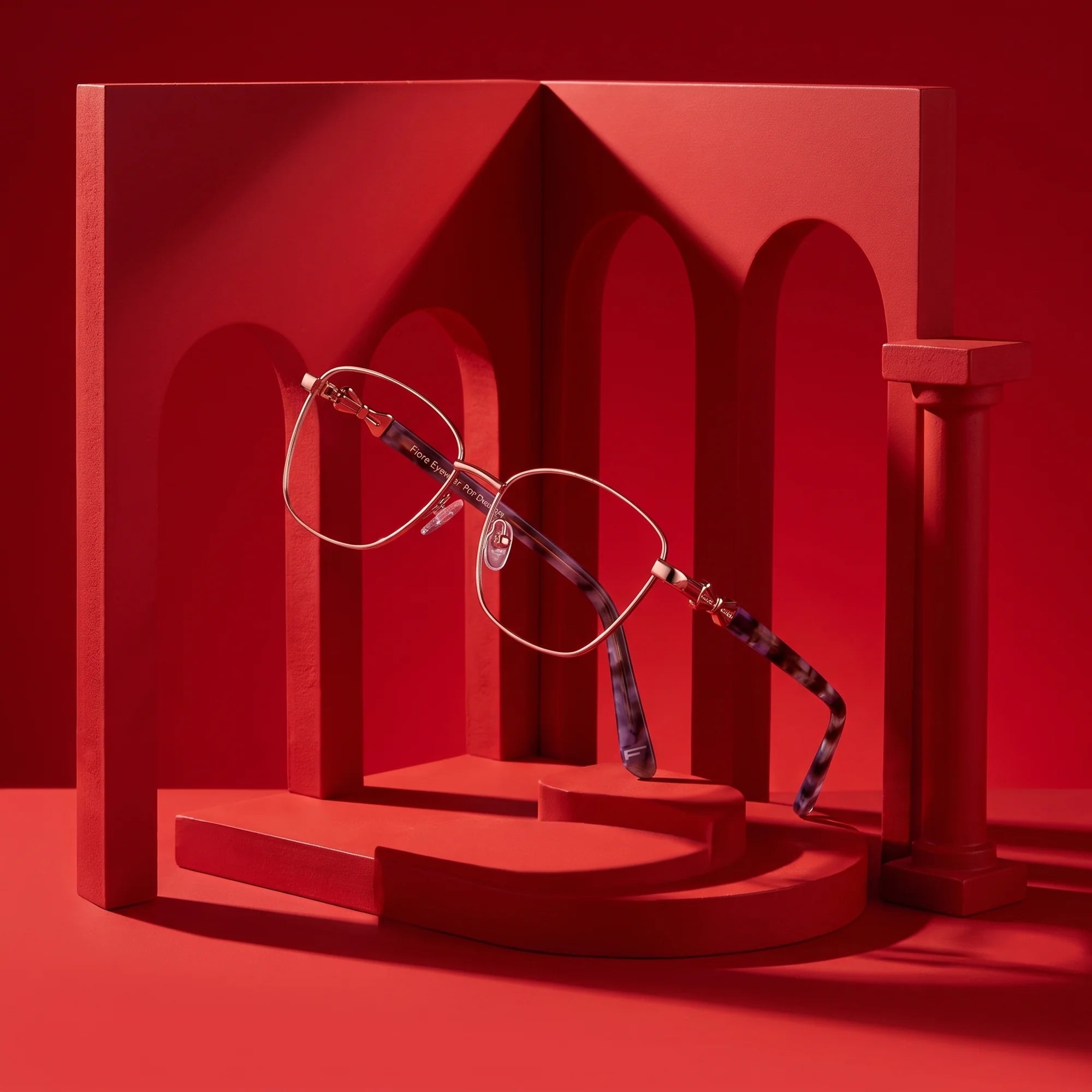 Fiore 22115 eyeglasses in gold – still life among monochrome vivid red arches
