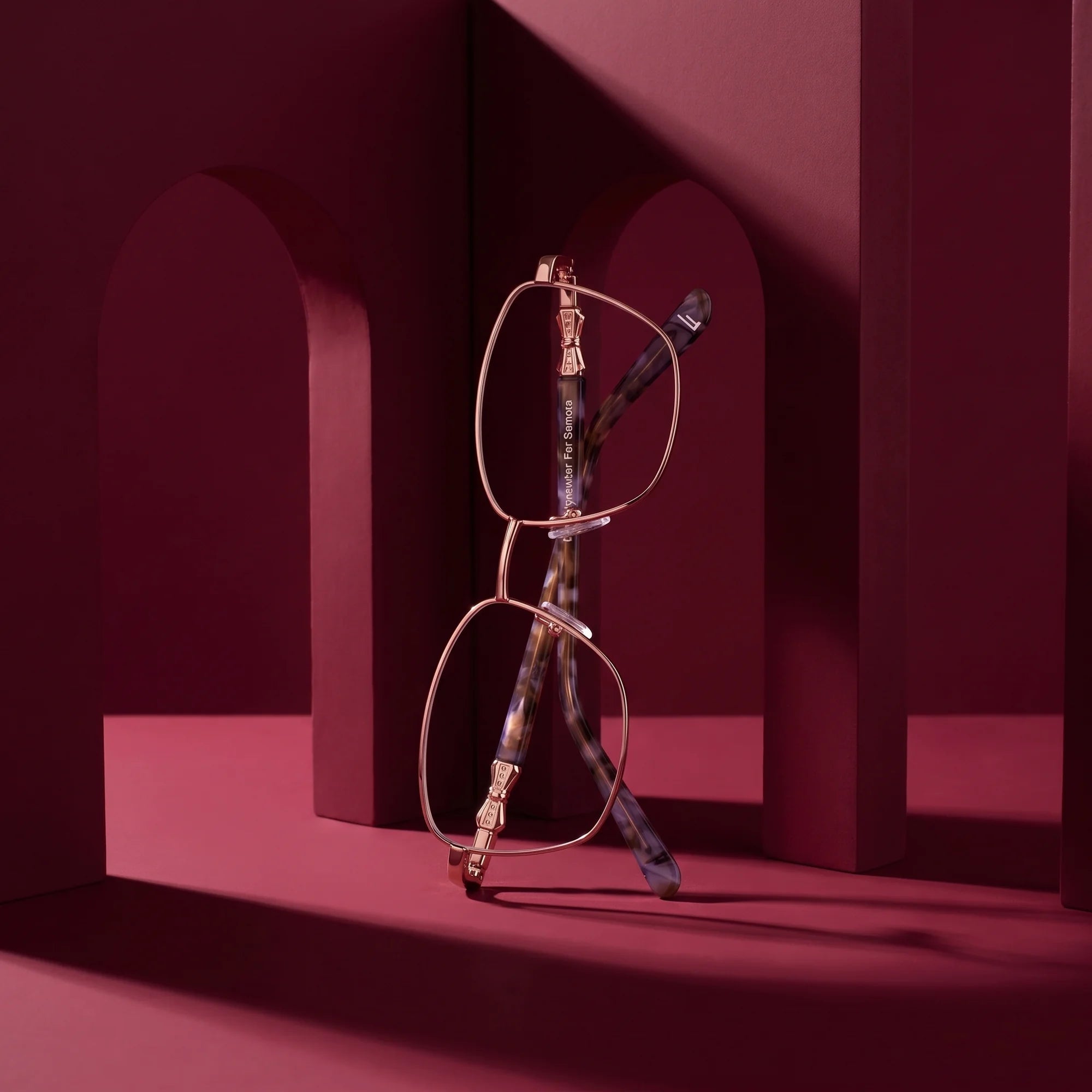 Fiore 22115 eyeglasses in gold – staged on a sculptural burgundy architecture set