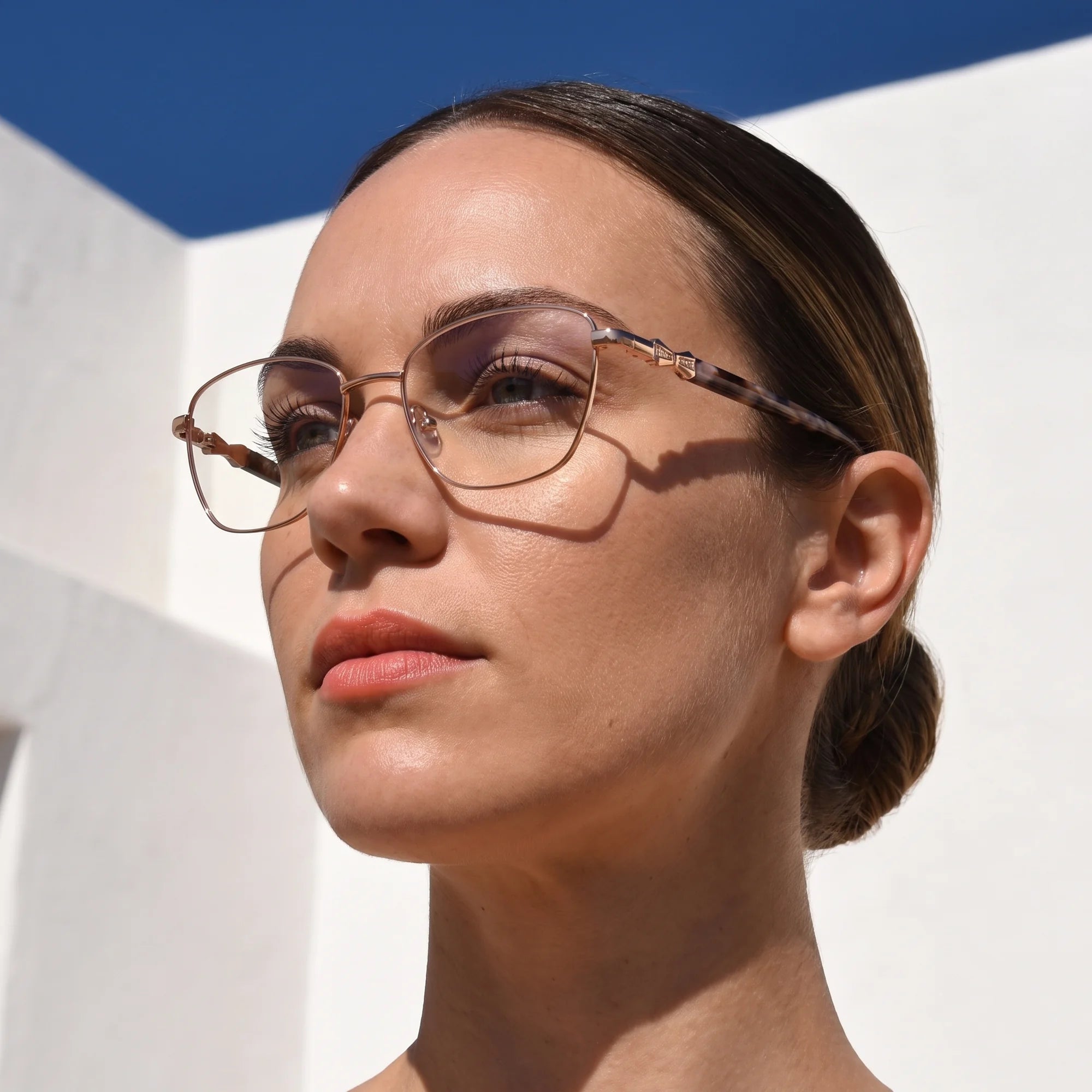 Fiore 22115 eyeglasses in gold, worn by a model – campaign portrait, sunlit Balearic whitewash and deep blue sky