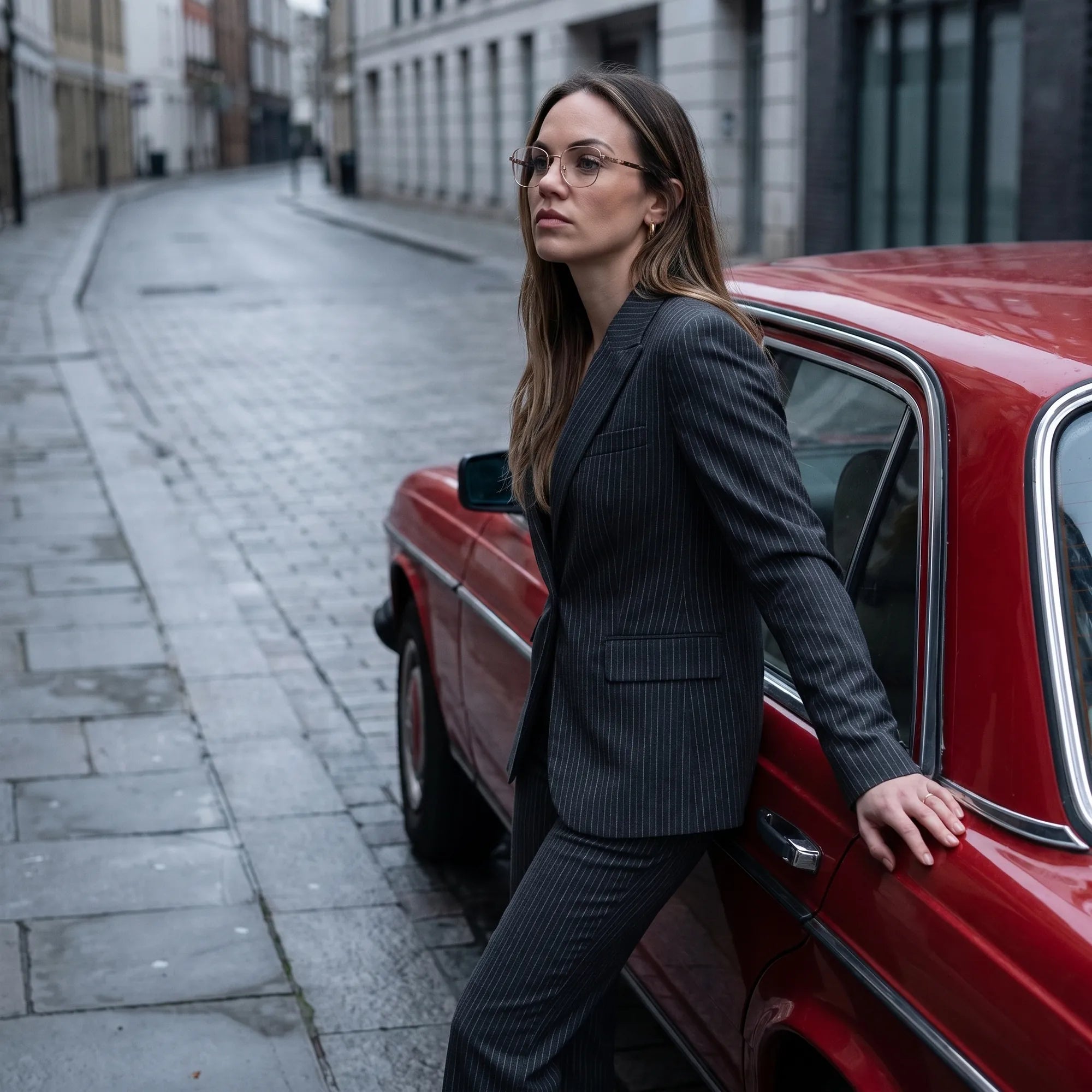 Fiore 22115 eyeglasses in gold, worn by a model – campaign portrait, pinstripe suit beside a classic red car