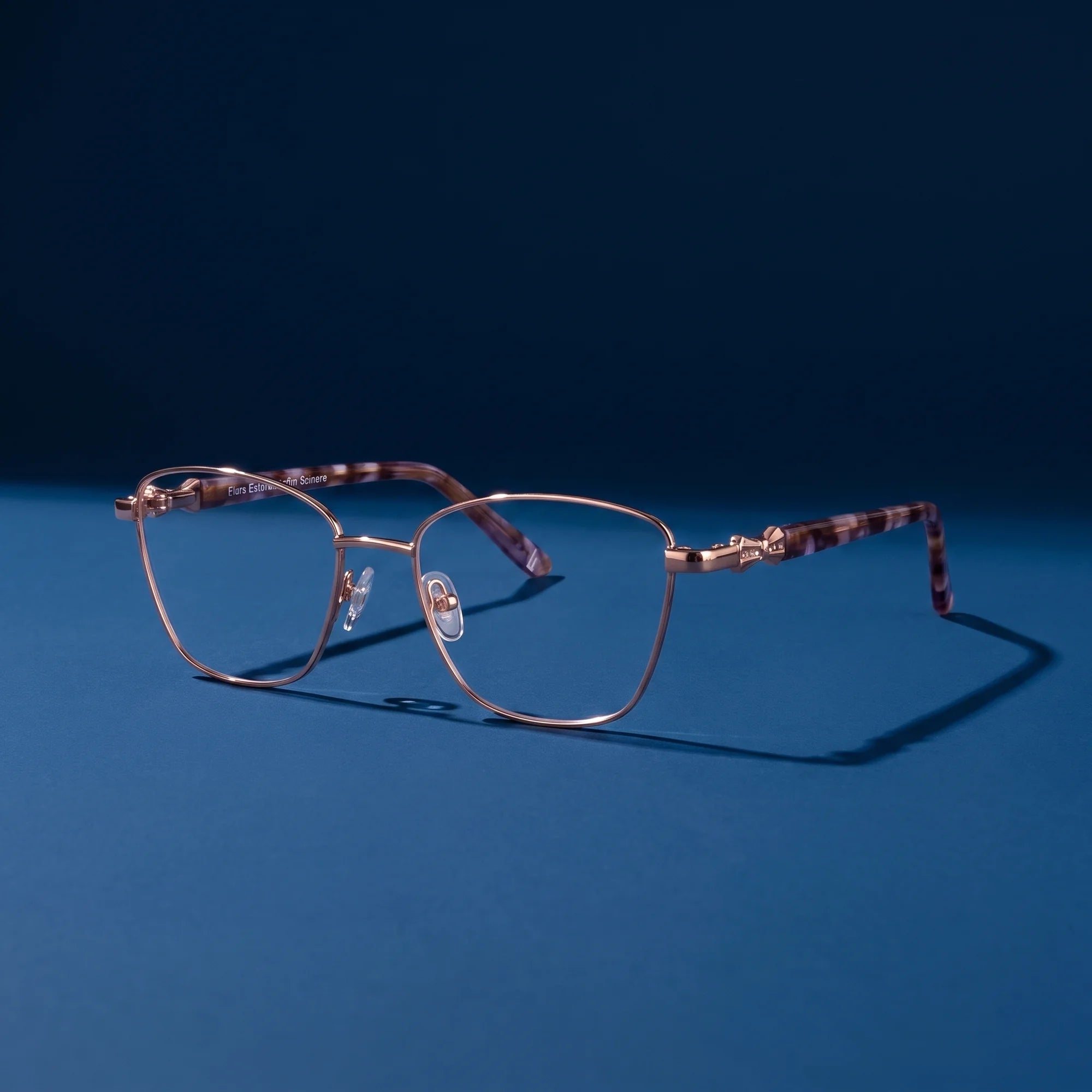 Fiore 22115 eyeglasses in gold – still life on a seamless midnight blue studio backdrop