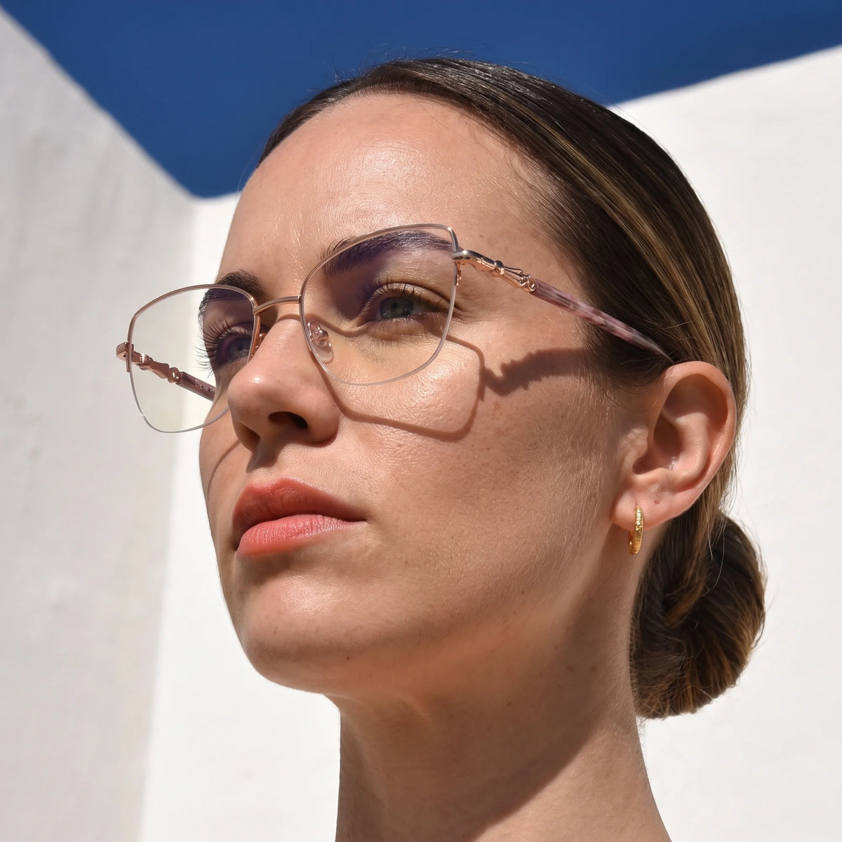 Fiore 22117 eyeglasses in gold, worn by a model – campaign portrait, sunlit Balearic whitewash and deep blue sky