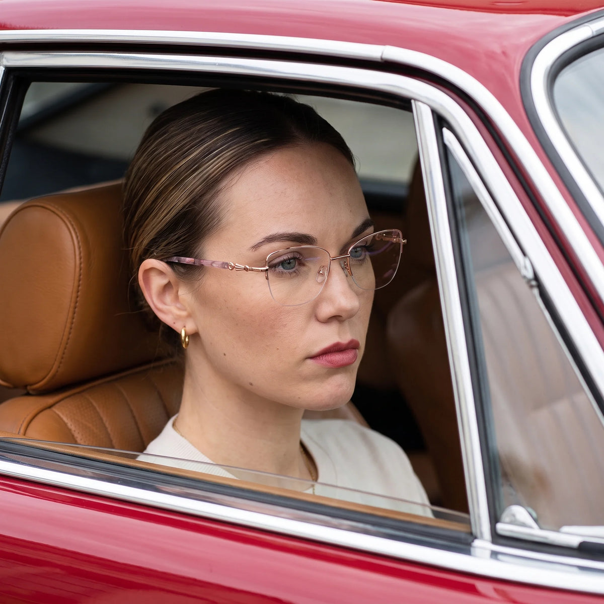 Fiore 22117 eyeglasses in gold, worn by a model – campaign portrait, gaze through a classic red car window