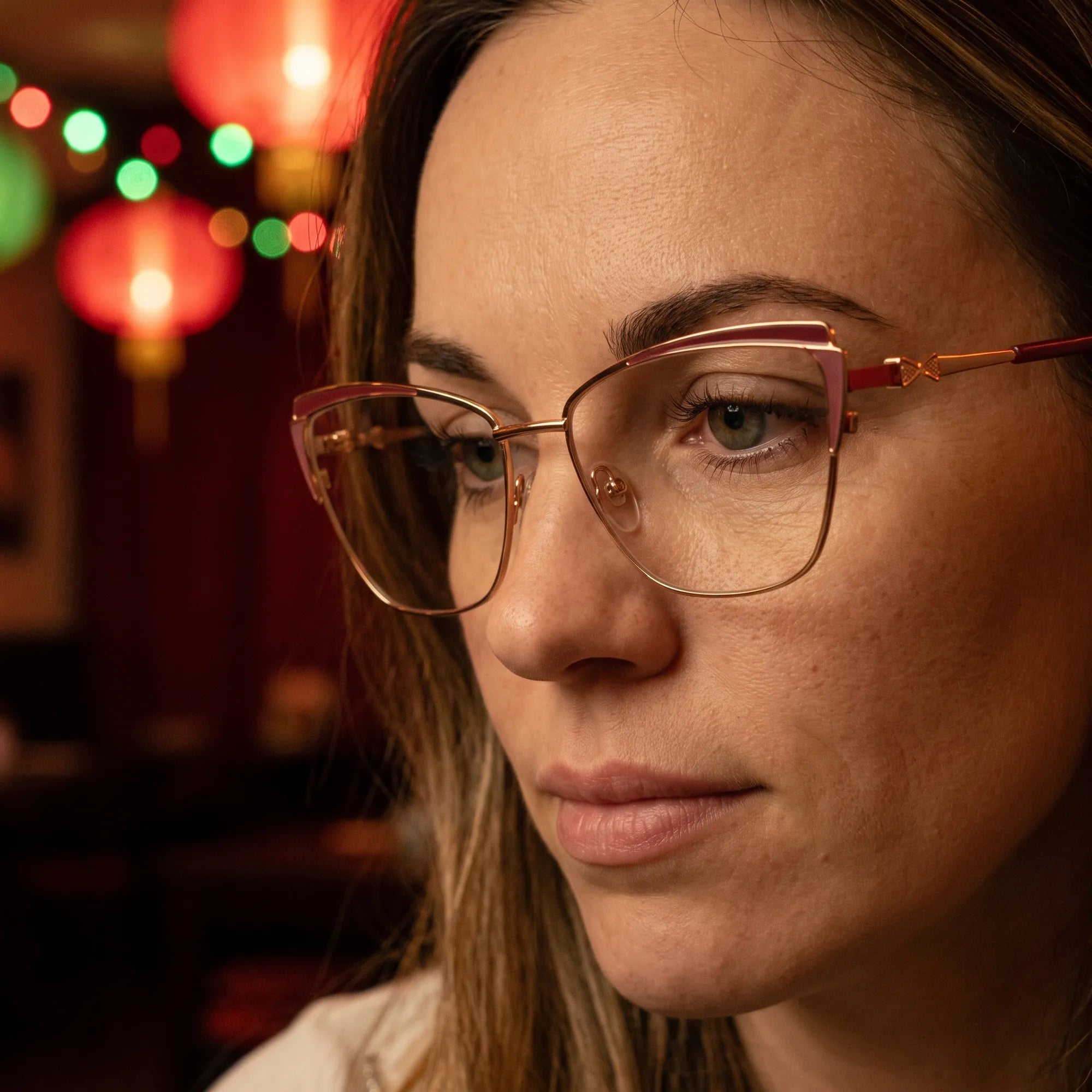 Fiore 3837 eyeglasses in red gold, worn by a model – campaign portrait, candid portrait in neon-lit evening glow
