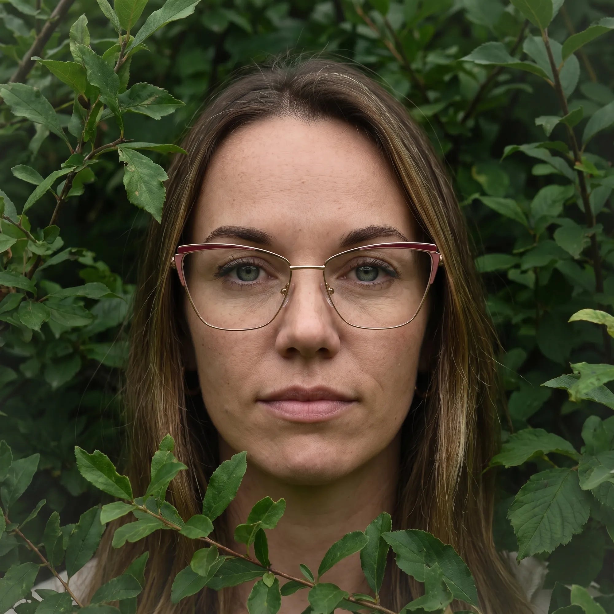 Fiore 3837 eyeglasses in red gold, worn by a model – campaign portrait, summer daydream in a garden armchair