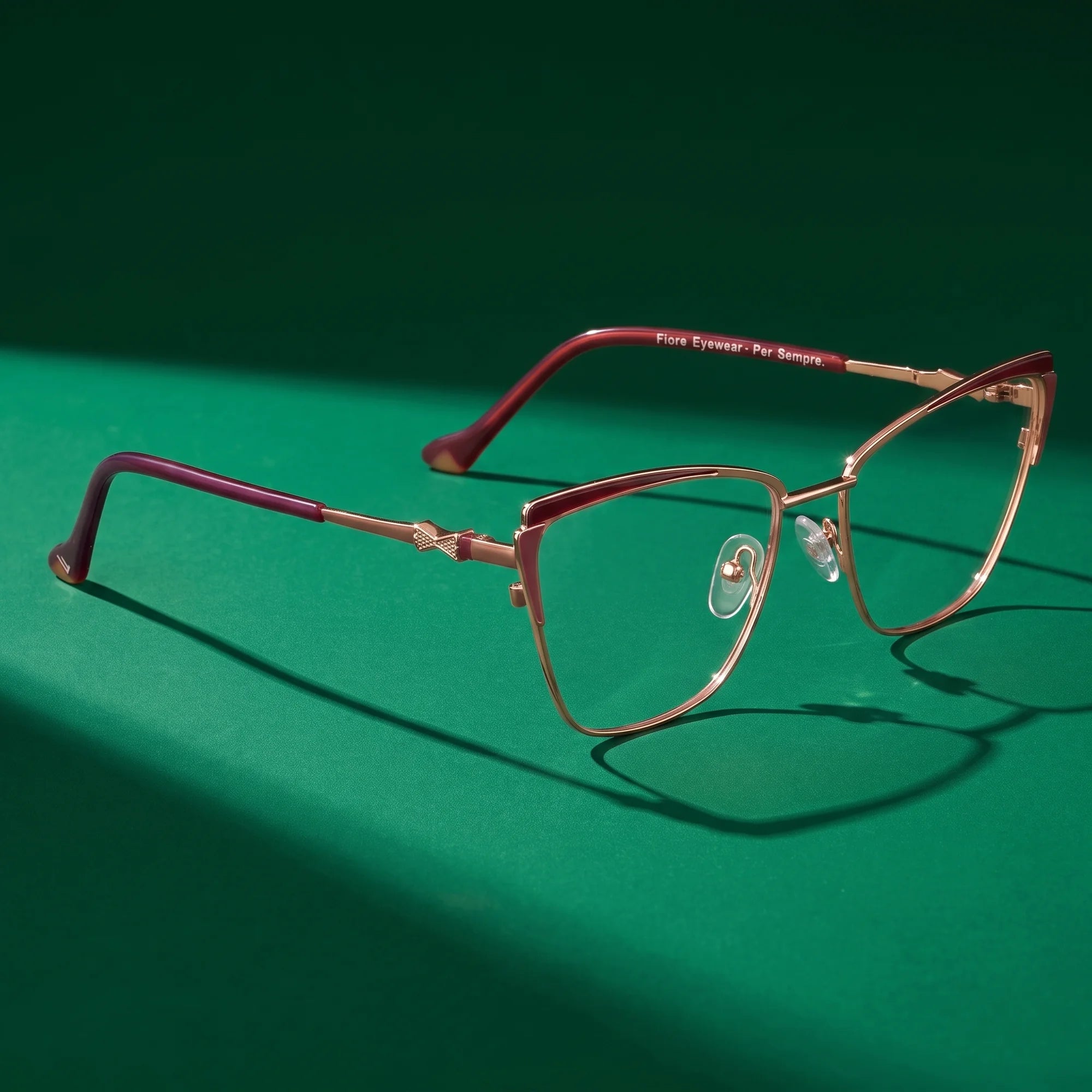 Fiore 3837 eyeglasses in red gold – editorial still life on a saturated emerald set