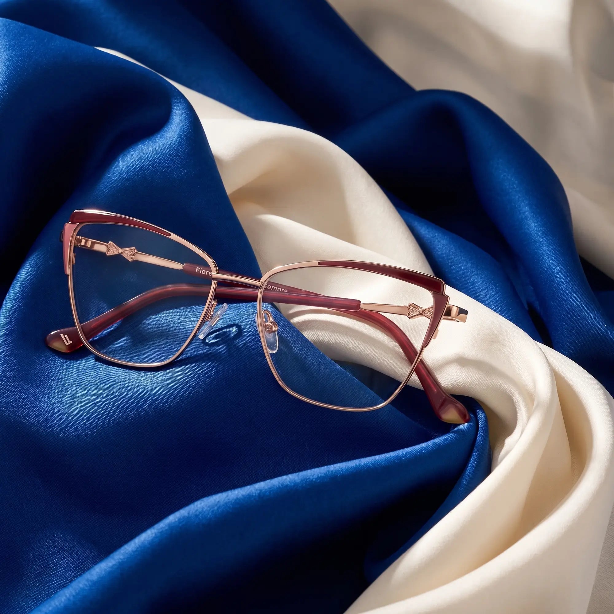 Fiore 3837 eyeglasses in red gold – resting on draped cobalt and ivory silk