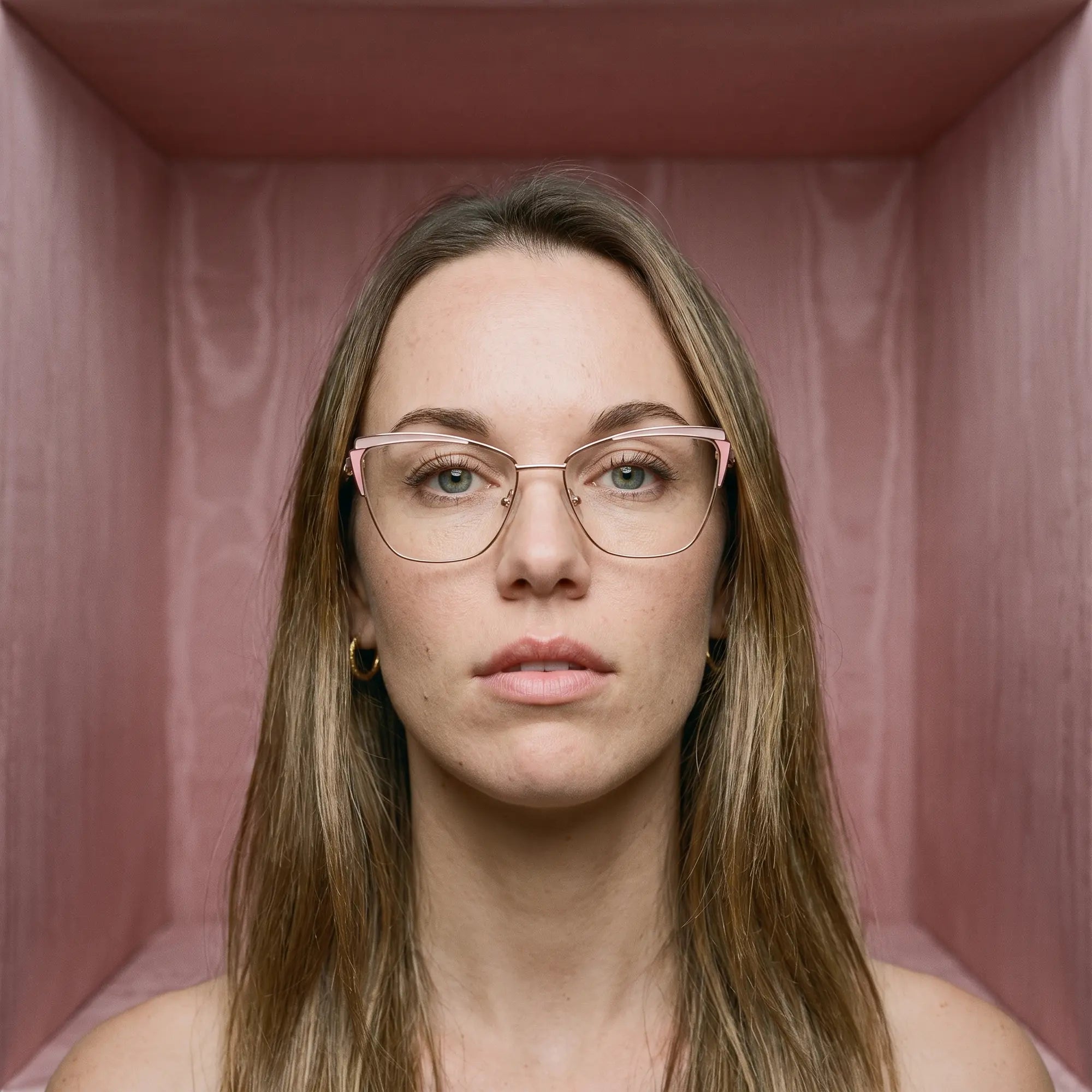 Fiore 3837 eyeglasses in pink gold, worn by a model – campaign portrait, face framed by rose moire upholstery