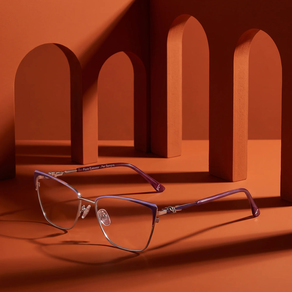 Fiore 3839 eyeglasses in purple silver – displayed on a burnt orange podium among arches