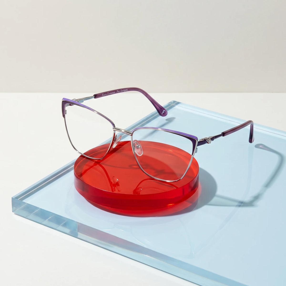 Fiore 3839 eyeglasses in purple silver – on a cobalt acrylic disc in soft daylight