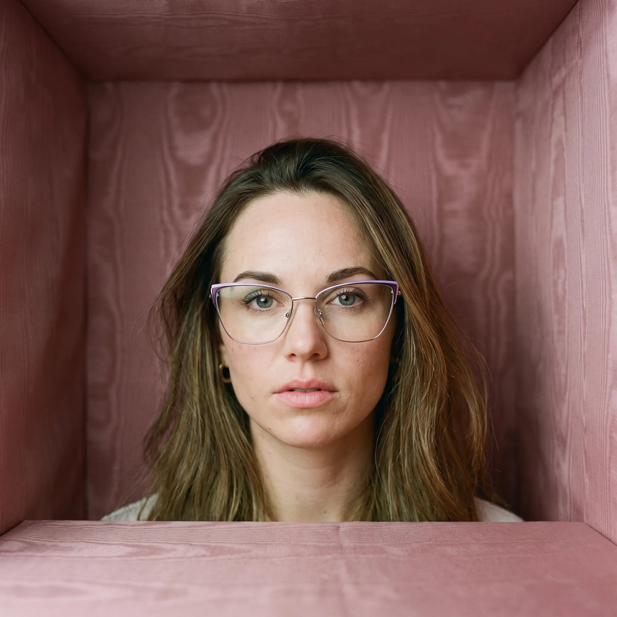Fiore 3839 eyeglasses in purple silver, worn by a model – campaign portrait, face framed by rose moire upholstery