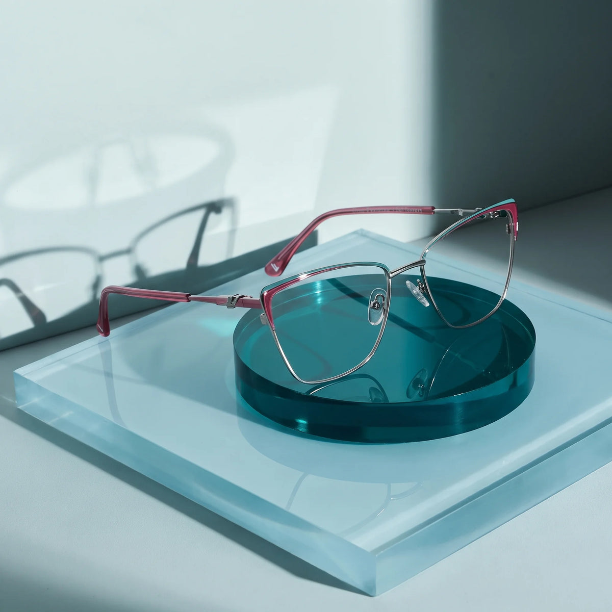 Fiore 3839 eyeglasses in red gun – on a cobalt acrylic disc in soft daylight