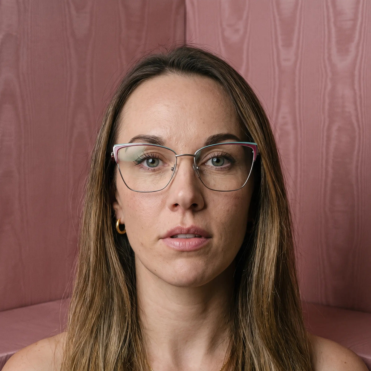 Fiore 3839 eyeglasses in red gun, worn by a model – campaign portrait, face framed by rose moire upholstery