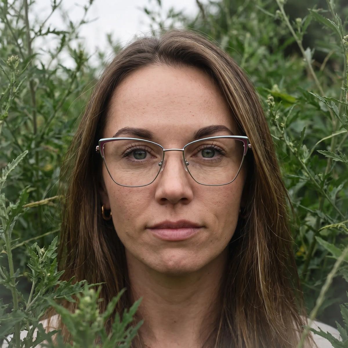 Fiore 3839 eyeglasses in red gun, worn by a model – campaign portrait, summer daydream in a garden armchair