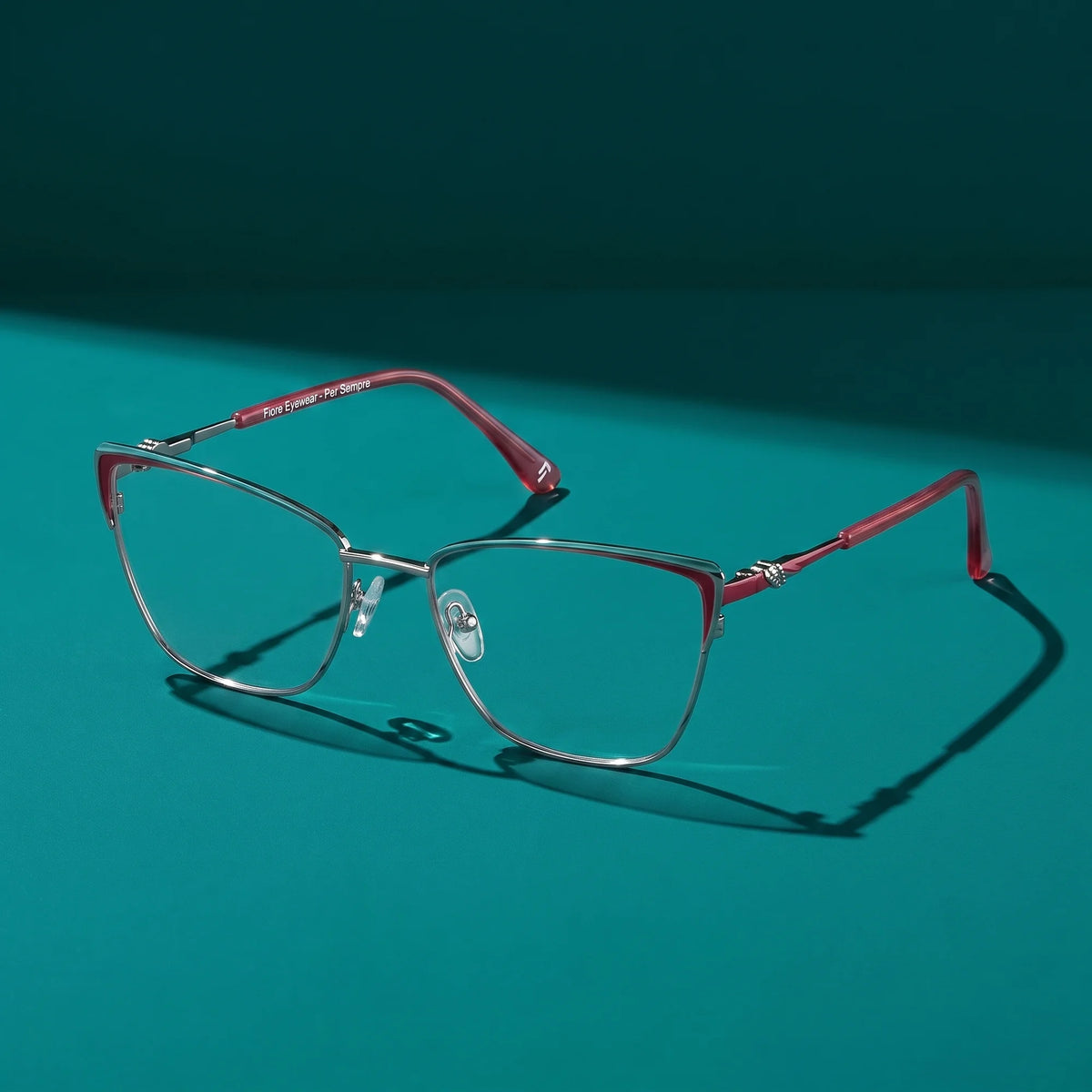 Fiore 3839 eyeglasses in red gun – still life on a seamless teal studio backdrop