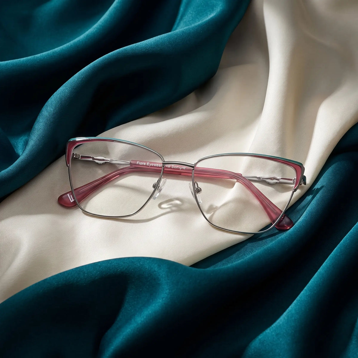 Fiore 3839 eyeglasses in red gun – resting on draped teal and ivory silk