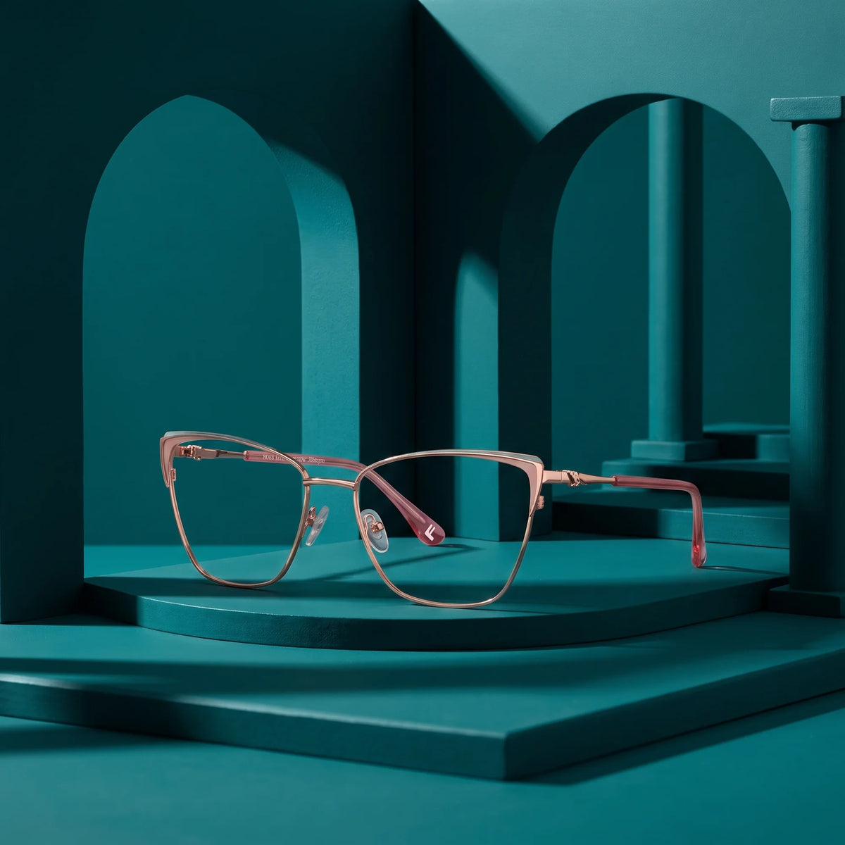 Fiore 3839 eyeglasses in pink gold – displayed on a teal podium among arches