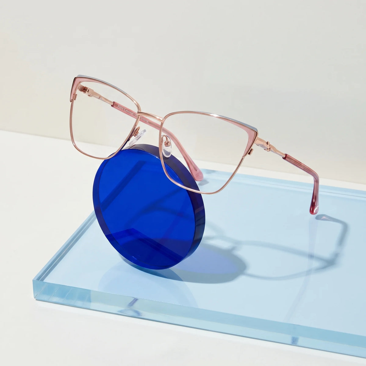 Fiore 3839 eyeglasses in pink gold – on a cobalt acrylic disc in soft daylight