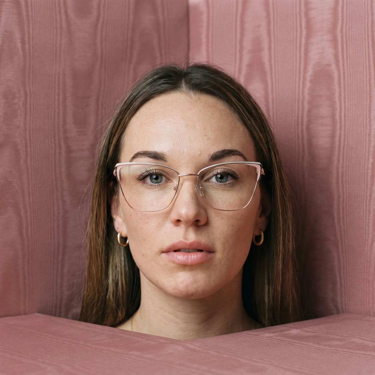 Fiore 3839 eyeglasses in pink gold, worn by a model – campaign portrait, face framed by rose moire upholstery