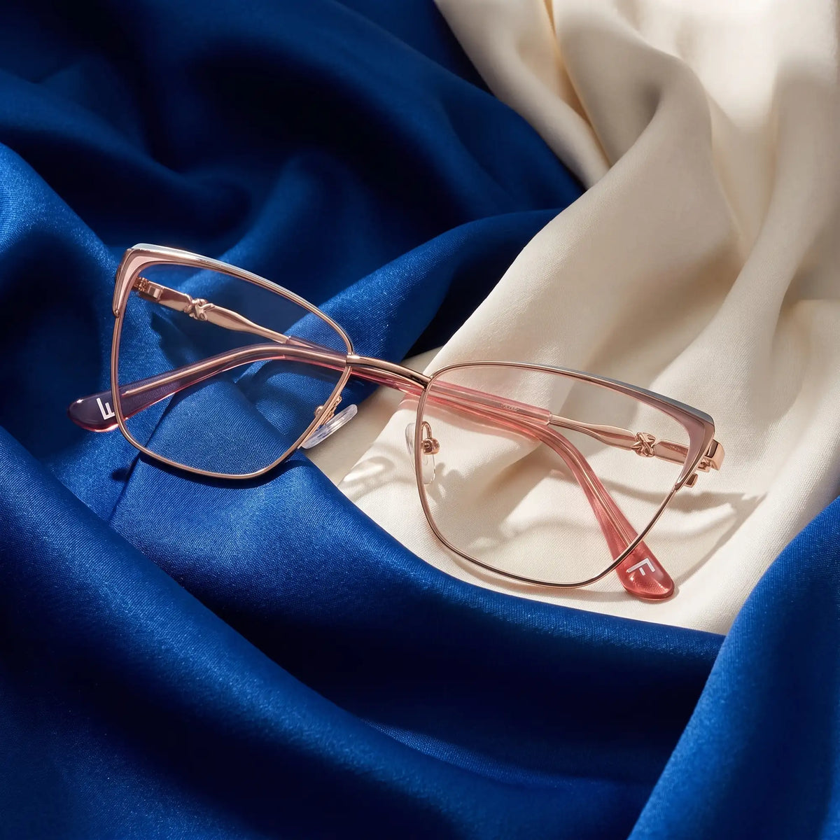 Fiore 3839 eyeglasses in pink gold – resting on draped cobalt and ivory silk