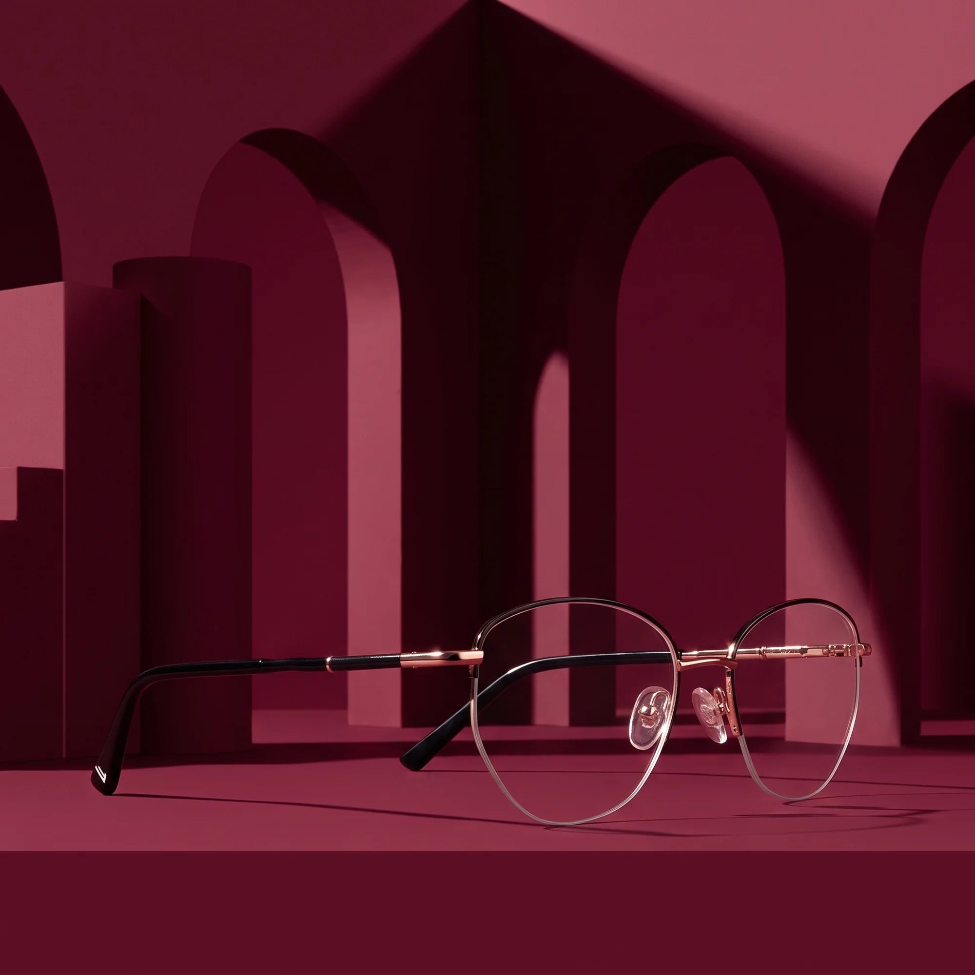 Fiore 3921 eyeglasses in black gold – displayed on a burgundy podium among arches