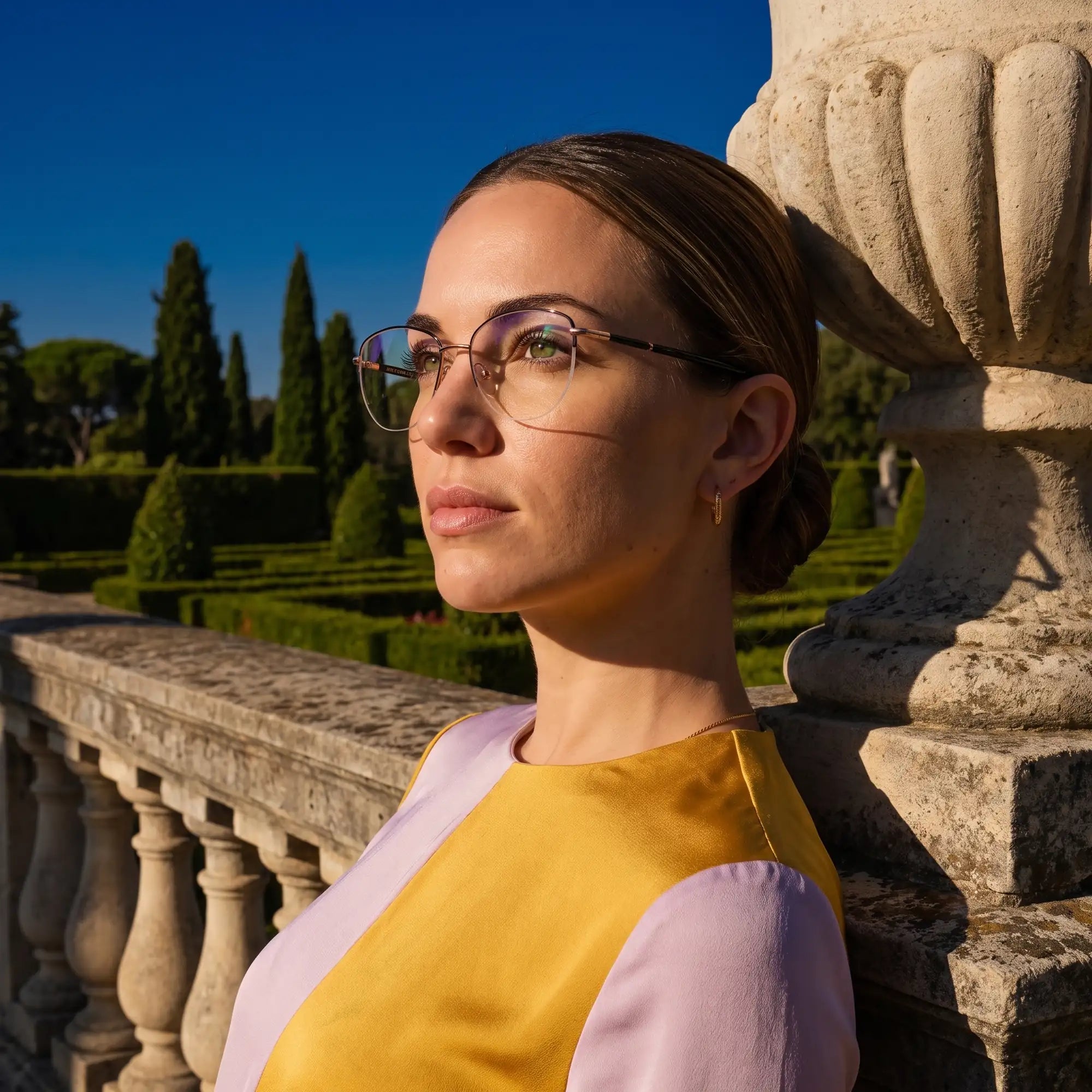 Fiore 3921 eyeglasses in black gold, worn by a model – campaign portrait, dusk light over a cypress garden