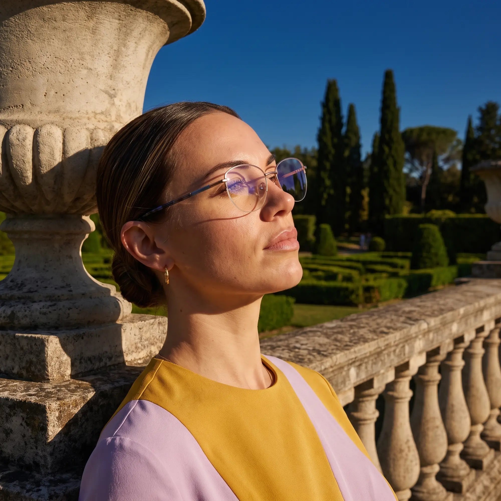 Fiore 3921 eyeglasses in grey brown, worn by a model – campaign portrait, dusk light over a cypress garden