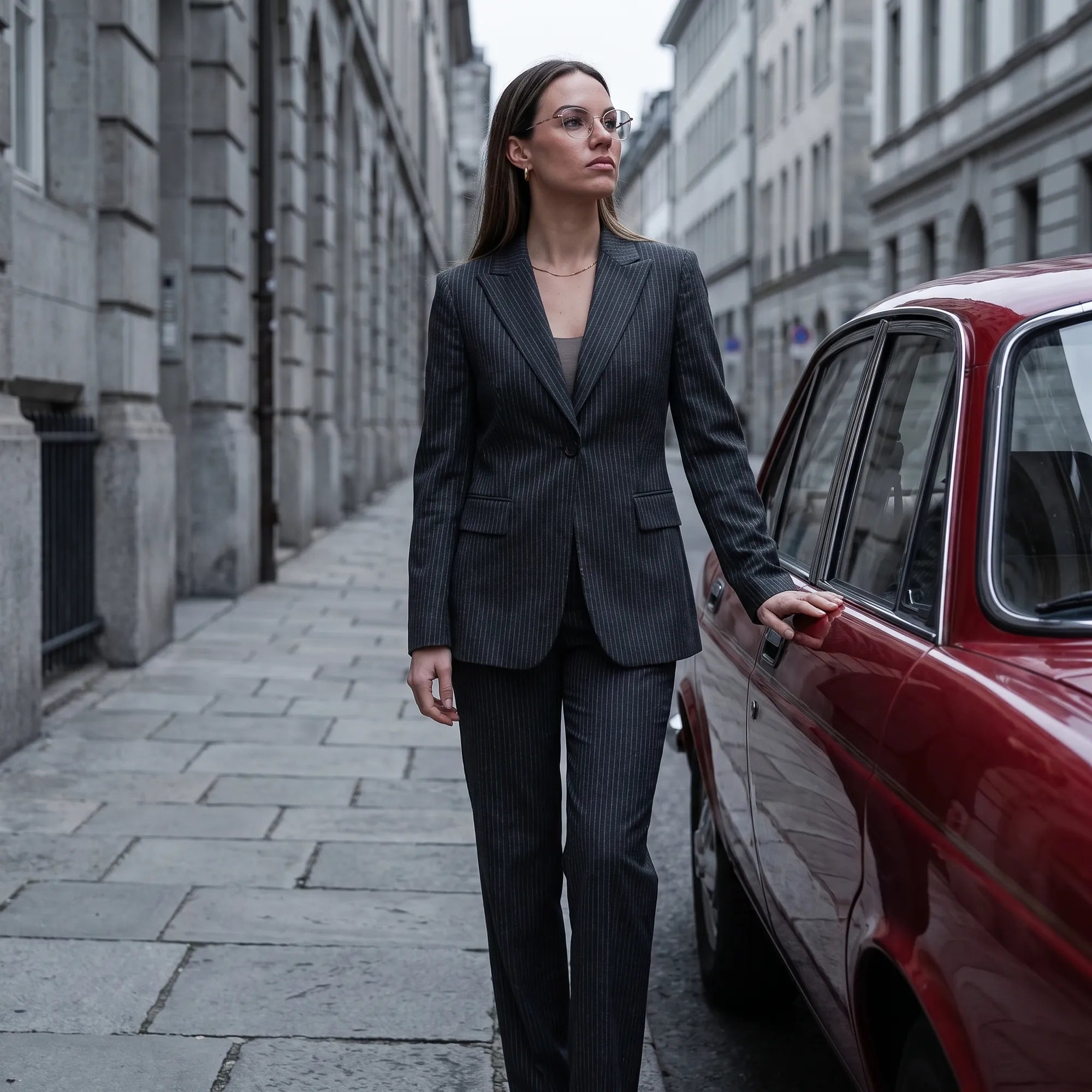 Fiore 3921 eyeglasses in grey brown, worn by a model – campaign portrait, pinstripe suit beside a classic red car