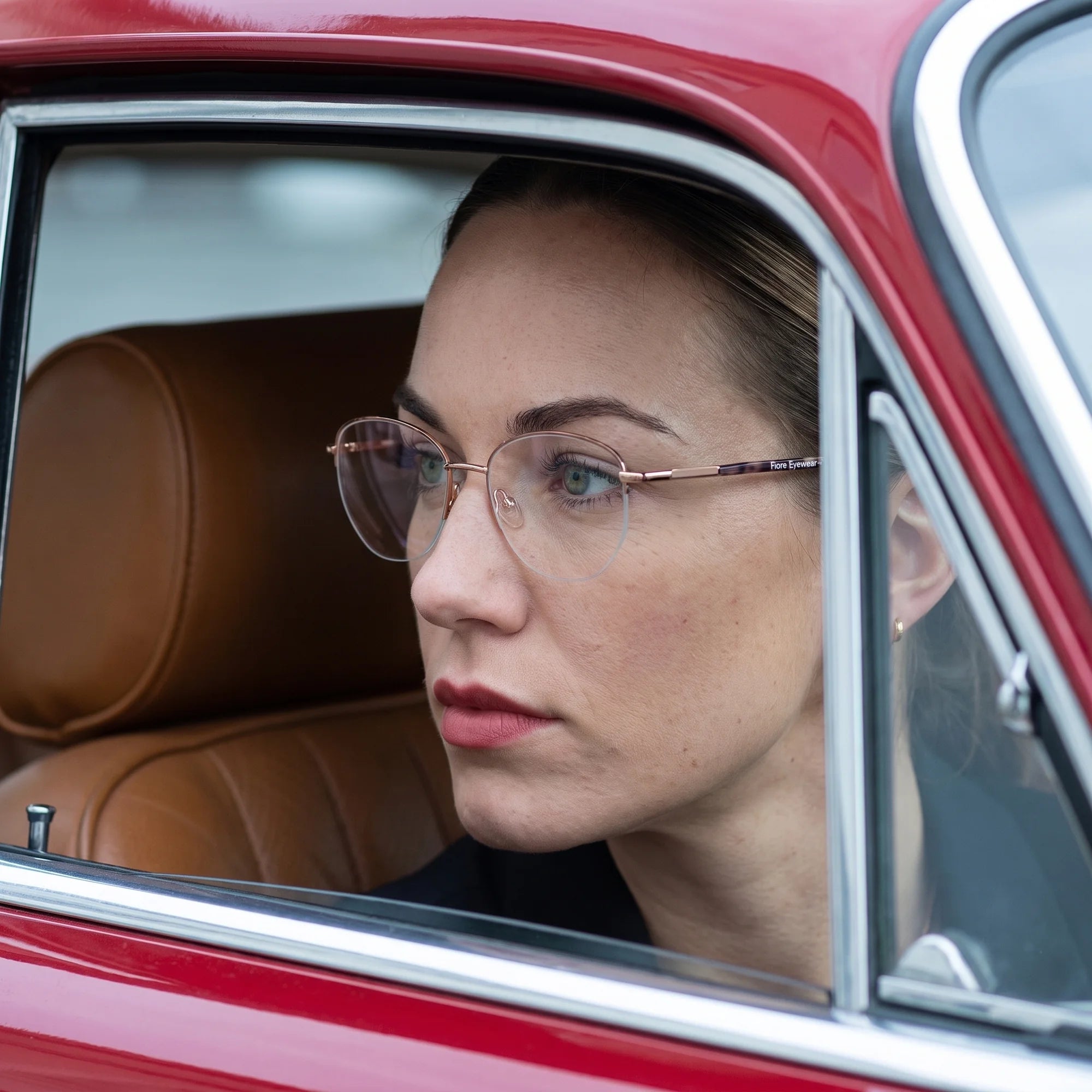 Fiore 3921 eyeglasses in brown gold, worn by a model – campaign portrait, gaze through a classic red car window