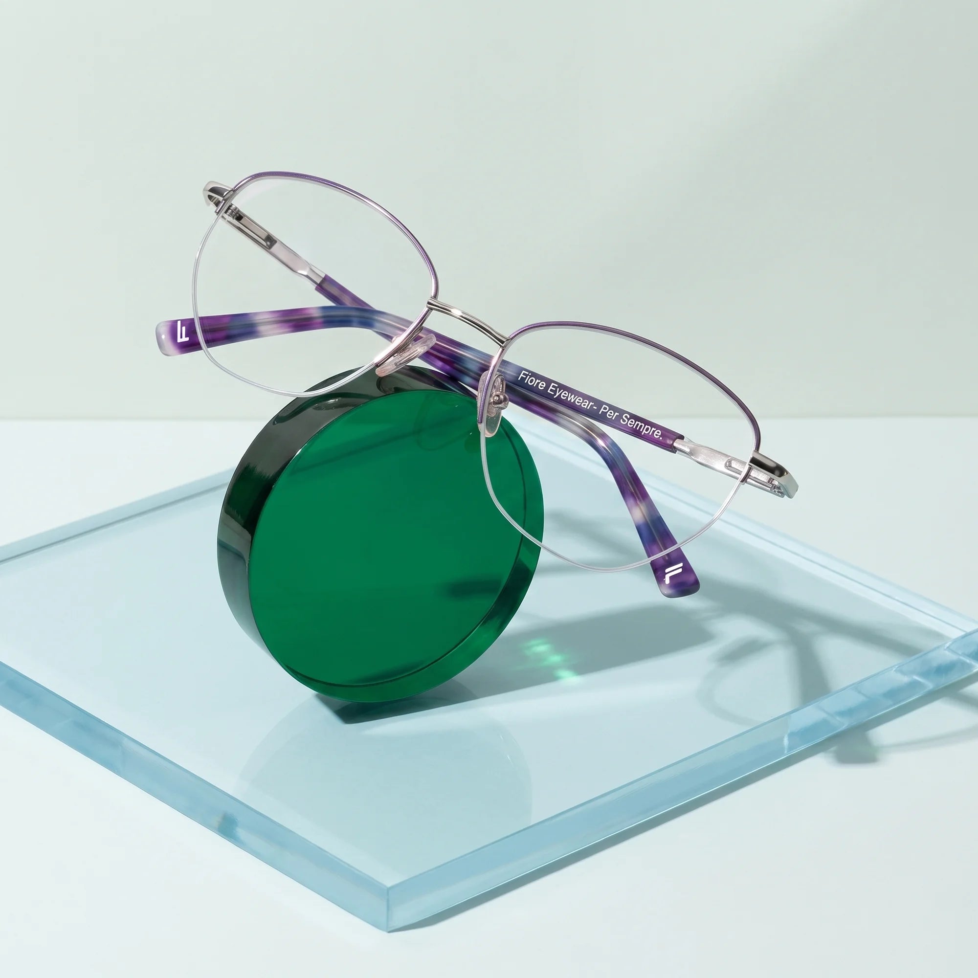 Fiore 3921 eyeglasses in purple silver – on a cobalt acrylic disc in soft daylight