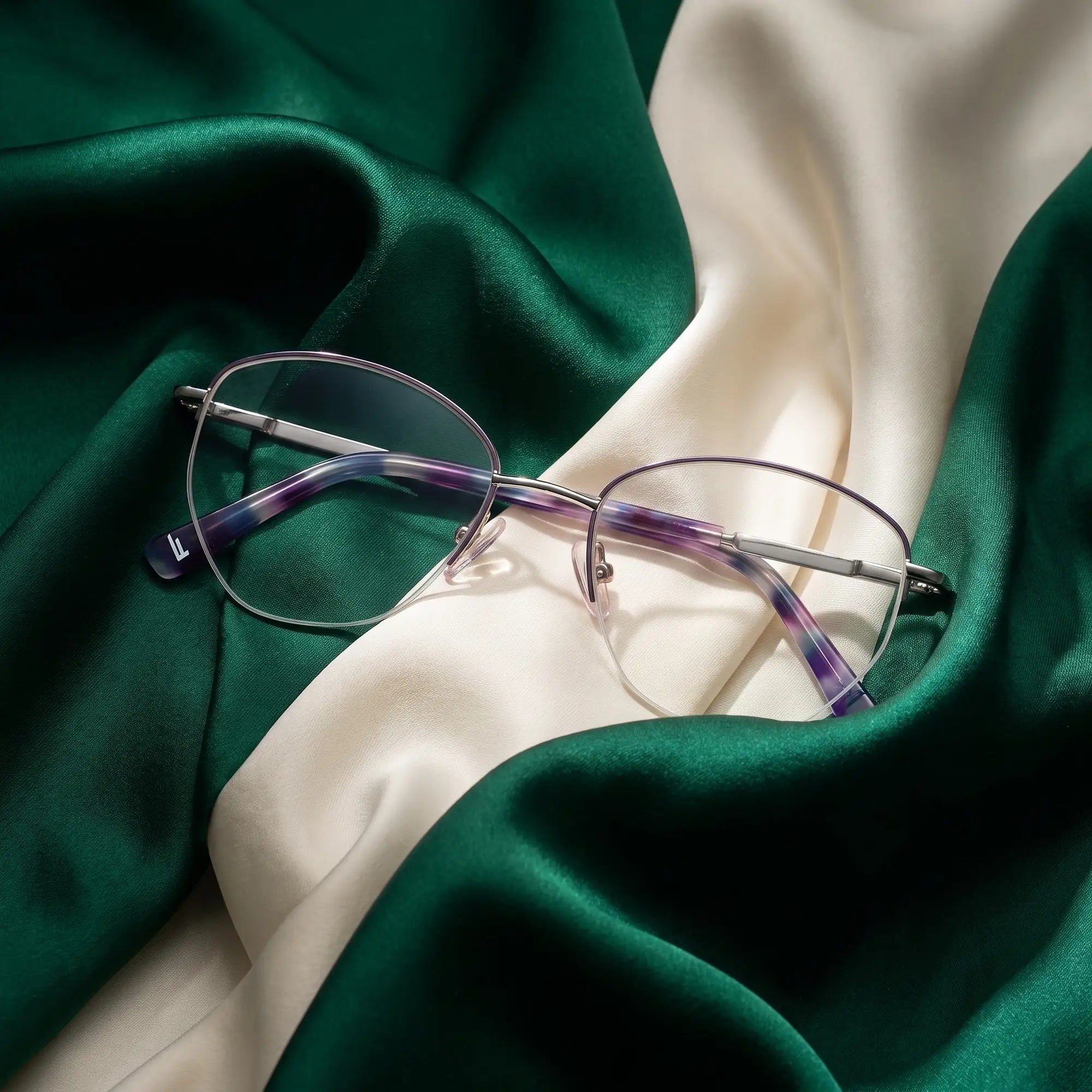 Fiore 3921 eyeglasses in purple silver – resting on draped emerald and ivory silk