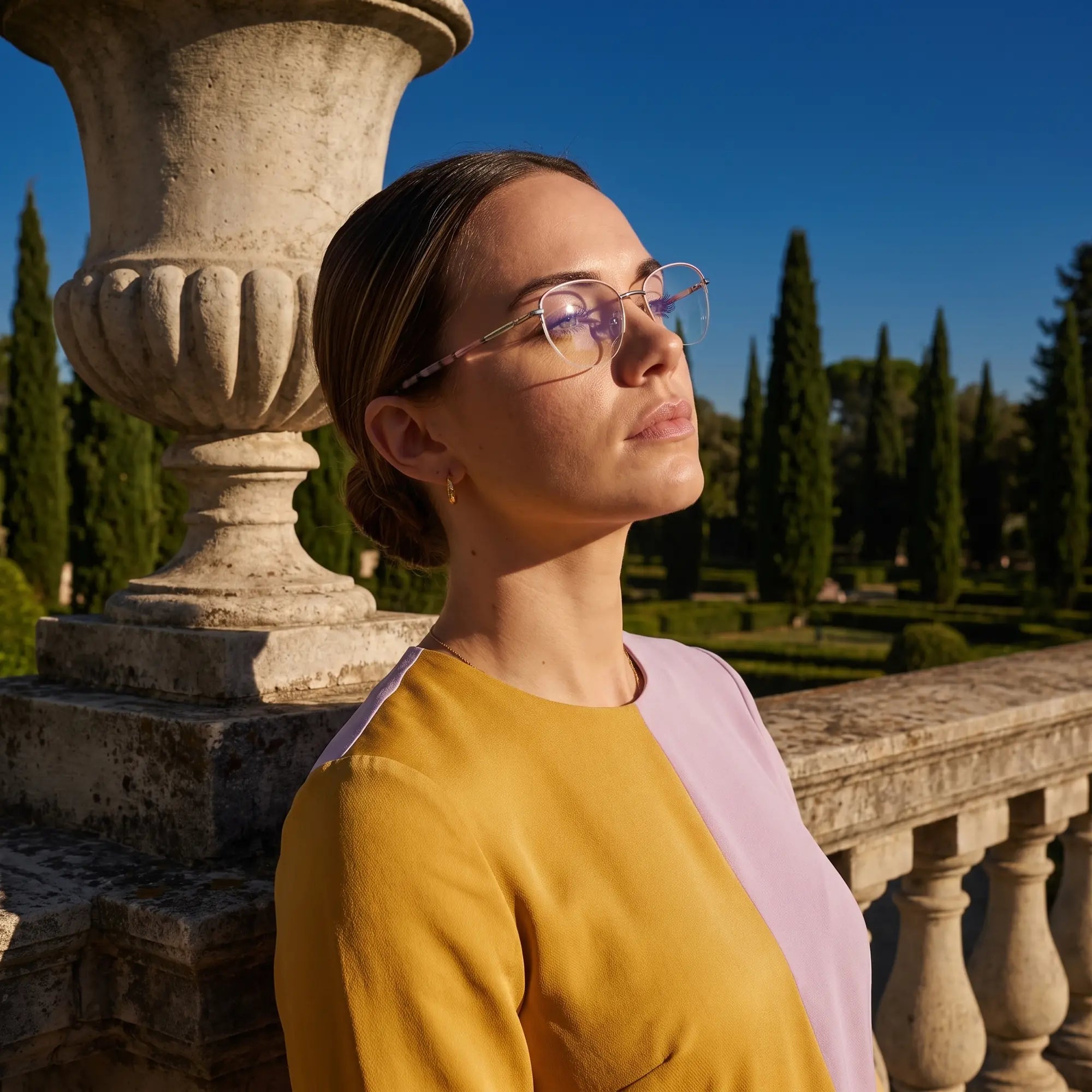 Fiore 3921 eyeglasses in pink silver, worn by a model – campaign portrait, dusk light over a cypress garden