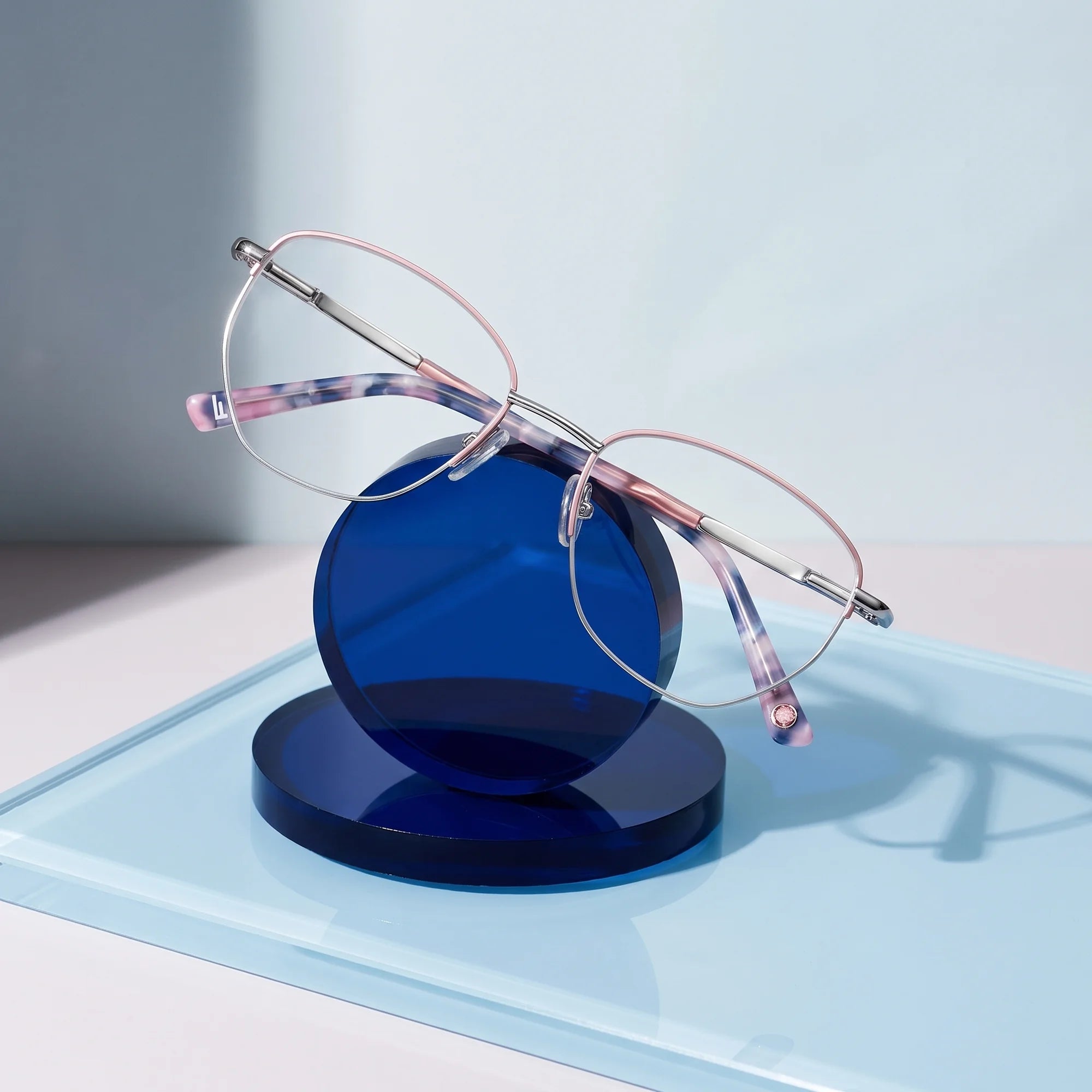 Fiore 3921 eyeglasses in pink silver – on a cobalt acrylic disc in soft daylight